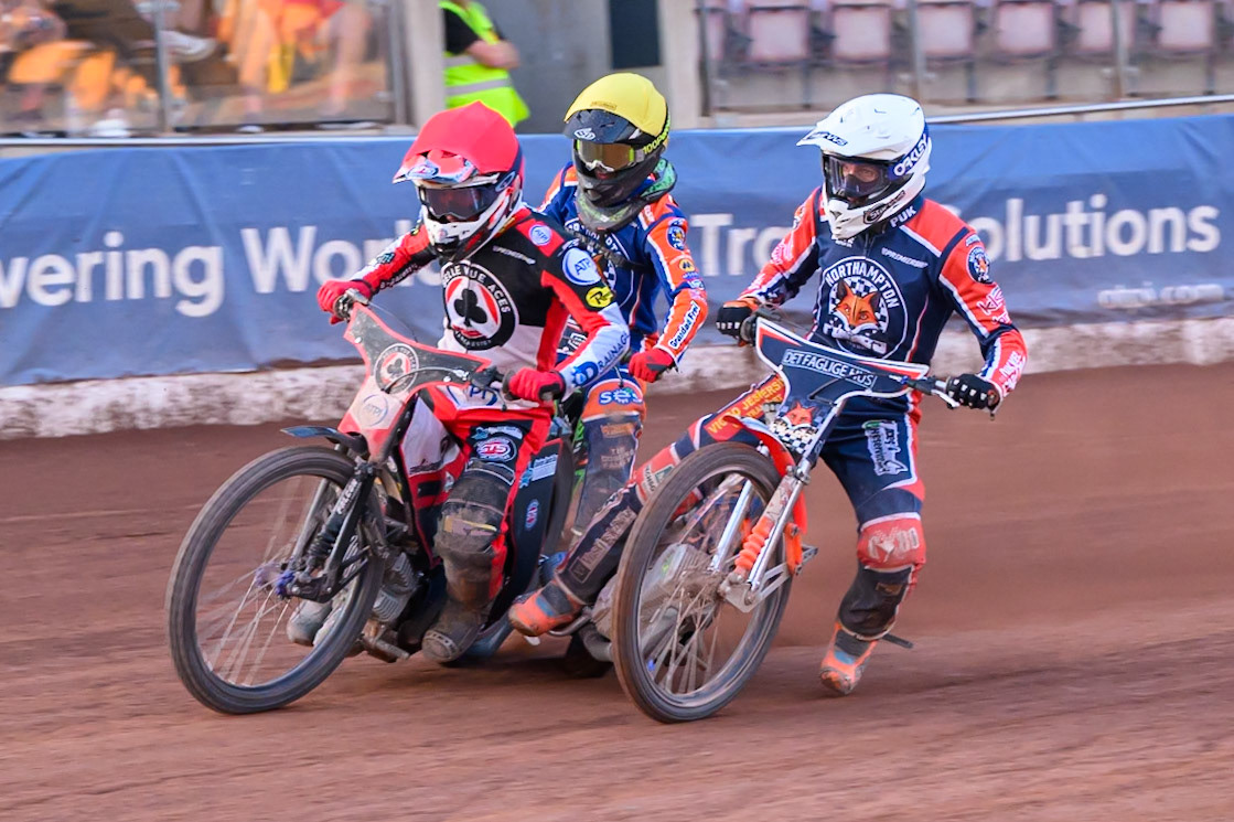 Niels-Kristian Iversen of Northampton Foxes in White rides inside Zach Cook of Belle Vue Aces  in Red and Luke Harrison of Northampton Foxes in Yellow during the Rowe Motor Oil Premiership match between Belle Vue Aces and Northampton Foxes at the National Speedway Stadium, Manchester on Monday 13th July 2026. (Photo: Ian Charles | MI News)
