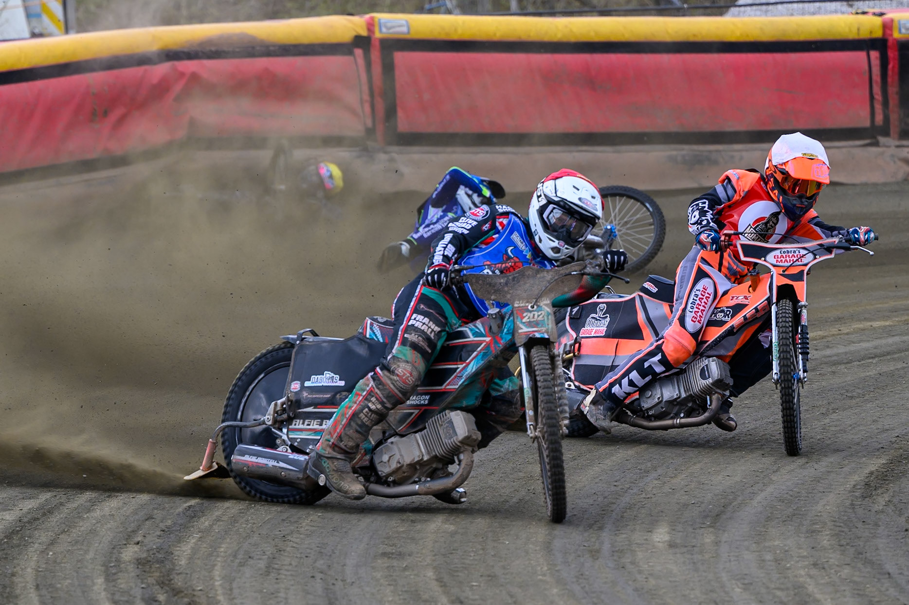 Alfie Bowtell of Buxton Bulls  in Red Connor Coles of NDL Nomads in White as Sam Woods of NDL Nomads  slides into the safety fence as Arran Butcher of Buxton Bulls  spins his machine during the  Challenge match between Buxton Bulls and NDL Nomads at Hi-Edge Speedway, Buxton on Sunday 19th April 2026. (Photo: Ian Charles | MI News)