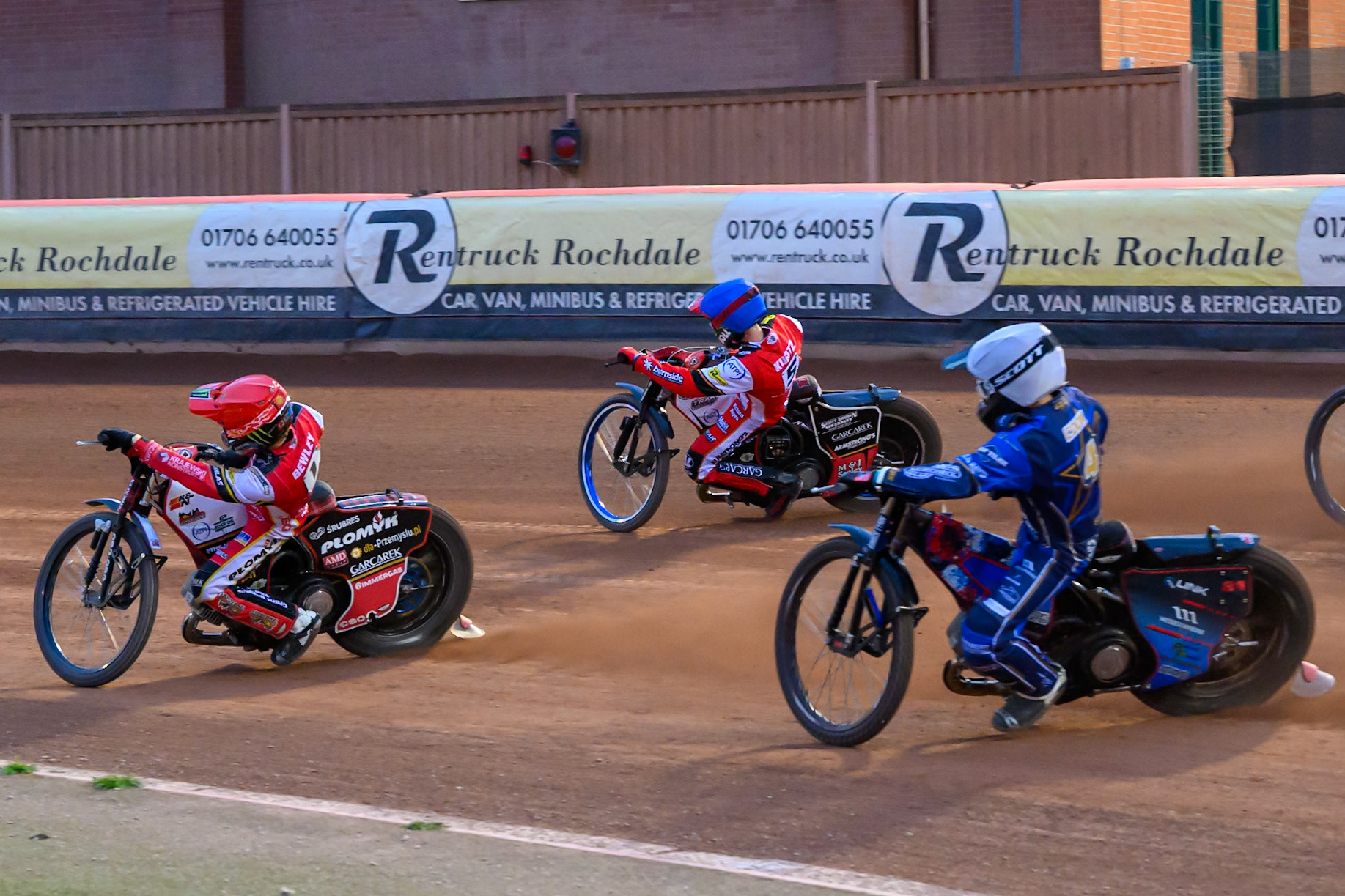 Kings Lynn Stars' Ben Cook in White chases Belle Vue Aces' Dan Bewley in Red and Belle Vue Aces' Brady Kurtz in Blue during the Rowe Motor Oil Premiership match between Belle Vue Aces and King's Lynn Stars at the National Speedway Stadium, Manchester on Monday 23rd June 2025. (Photo: Ian Charles | MI News)