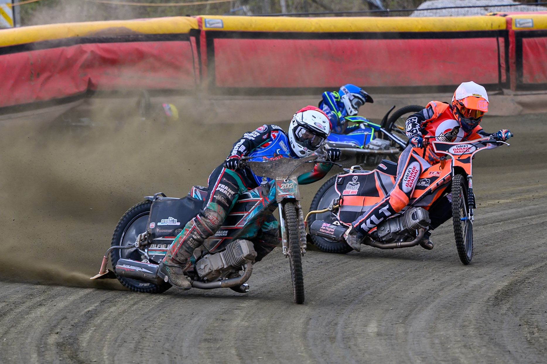 Alfie Bowtell of Buxton Bulls  in Red Connor Coles of NDL Nomads in White as Sam Woods of NDL Nomads  slides into the safety fence as Arran Butcher of Buxton Bulls  spins his machine during the  Challenge match between Buxton Bulls and NDL Nomads at Hi-Edge Speedway, Buxton on Sunday 19th April 2026. (Photo: Ian Charles | MI News)