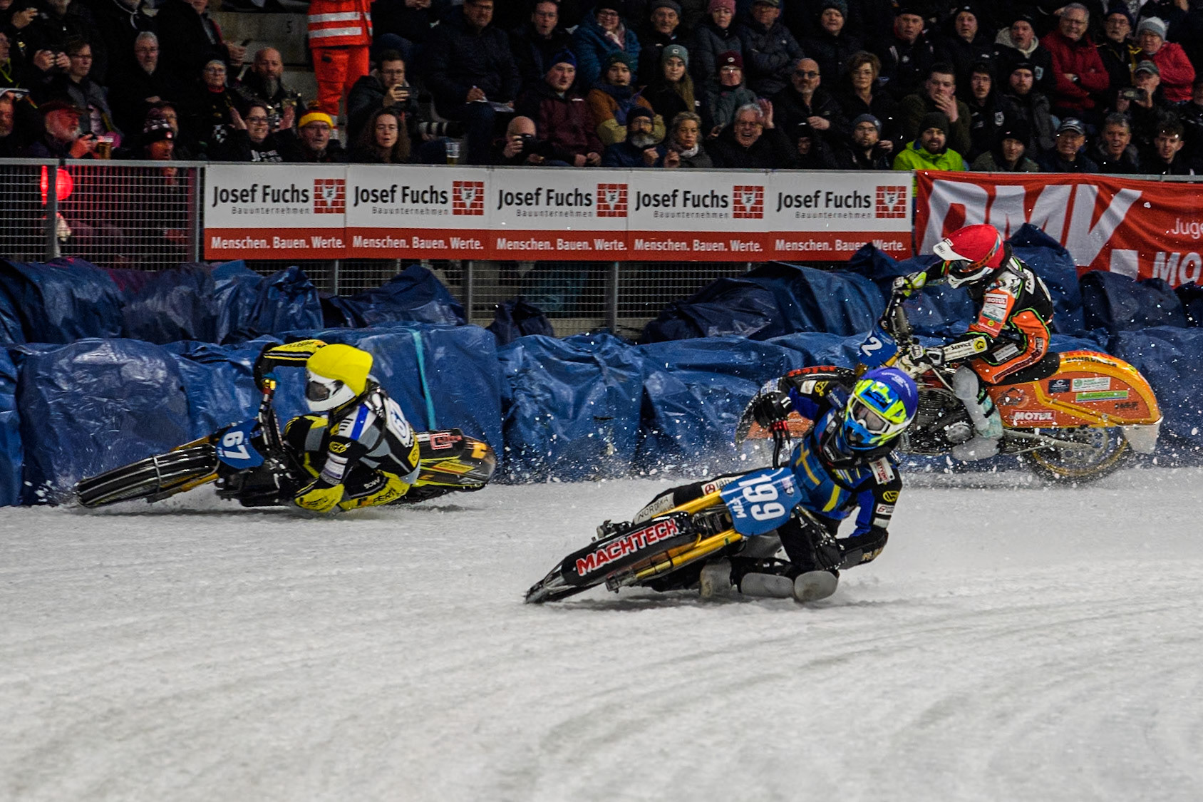 Sweden's Martin Haarahiltunen (199)  (Blue) leads  and Germany's Markus Jell (82) (Red) and Finland's Heikki Huusko (67)y\ collide and crash into the bales during the FIM Ice Speedway Gladiators World Championship Final 2 at the Max-Aicher-Arena, Inzell on Sunday 24 March 2024. (Photo: Ian Charles | MI News)
