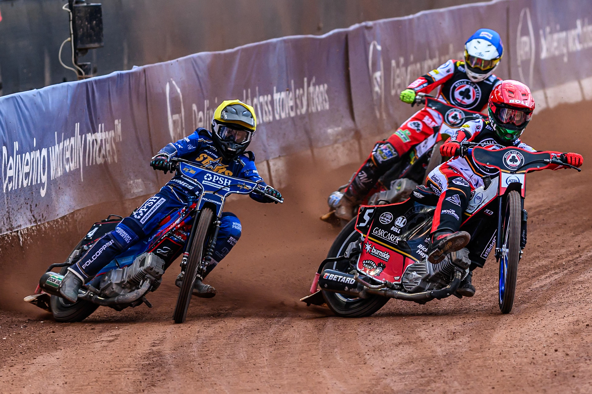 Belle Vue Aces' Brady Kurtz in Red rides inside Kings Lynn Stars' Ben Cook in Yellow with Belle Vue Aces' Tate Zischke in Blue behind during the Rowe Motor Oil Premiership match between Belle Vue Aces and King's Lynn Stars at the National Speedway Stadium, Manchester on Monday 23rd June 2025. (Photo: Ian Charles | MI News)