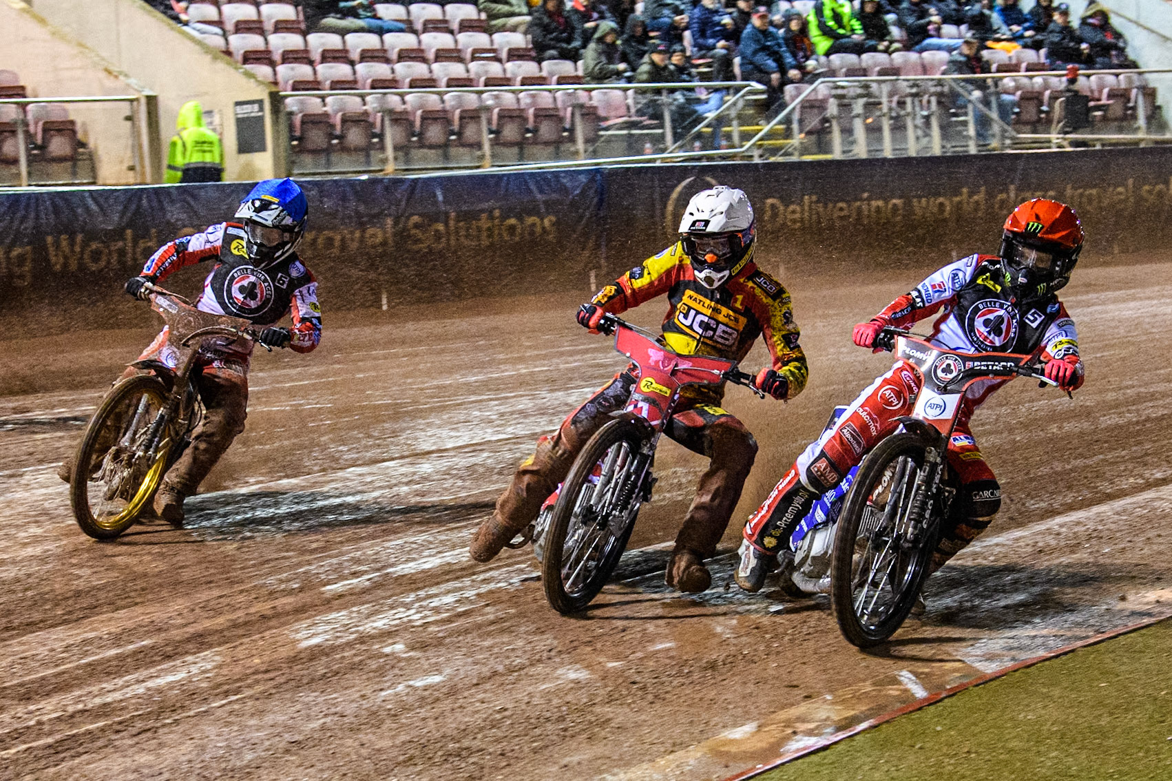 Dan Bewley of Belle Vue Aces in Red rides inside Max Fricke of Leicester Lions in White and Connor Mountain of Belle Vue Aces in Blue during the Rowe Motor Oil Premiership match between Belle Vue Aces and Leicester Lions at the National Speedway Stadium, Manchester on Saturday 6th April 2024. (Photo: Ian Charles | MI News)