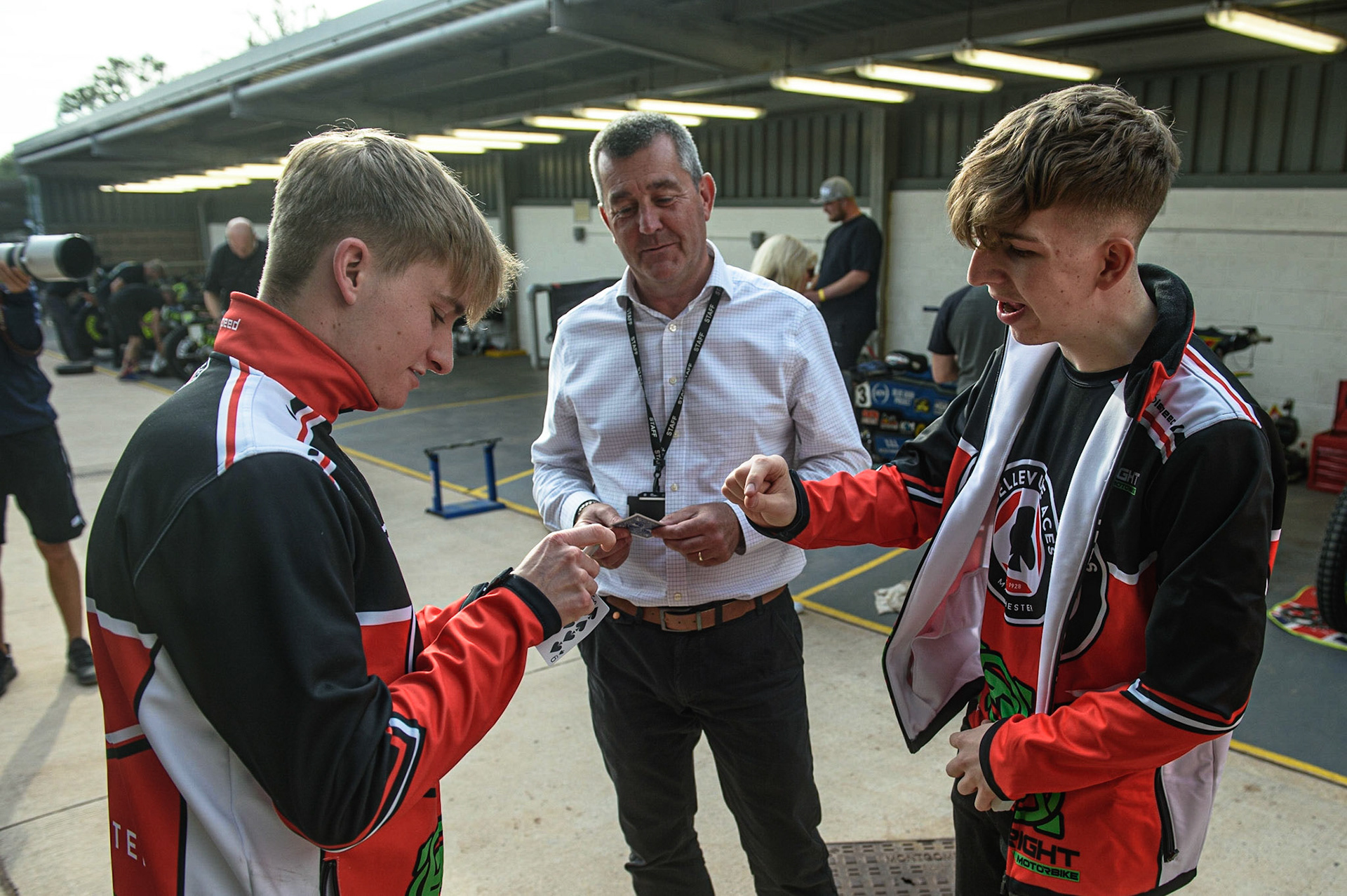 MANCHESTER UKClose up Magician Dan’The Magic Man’ Rhodes does some close up card tricks for Tom Brennan (left) and Belle Vue CEO Adrian Smith during the SGB Premiership match between Belle Vue Aces and Ipswich Witches at the National Speedway Stadium, Manchester on Monday 2nd August 2021. (Credit: Ian Charles | MI News)