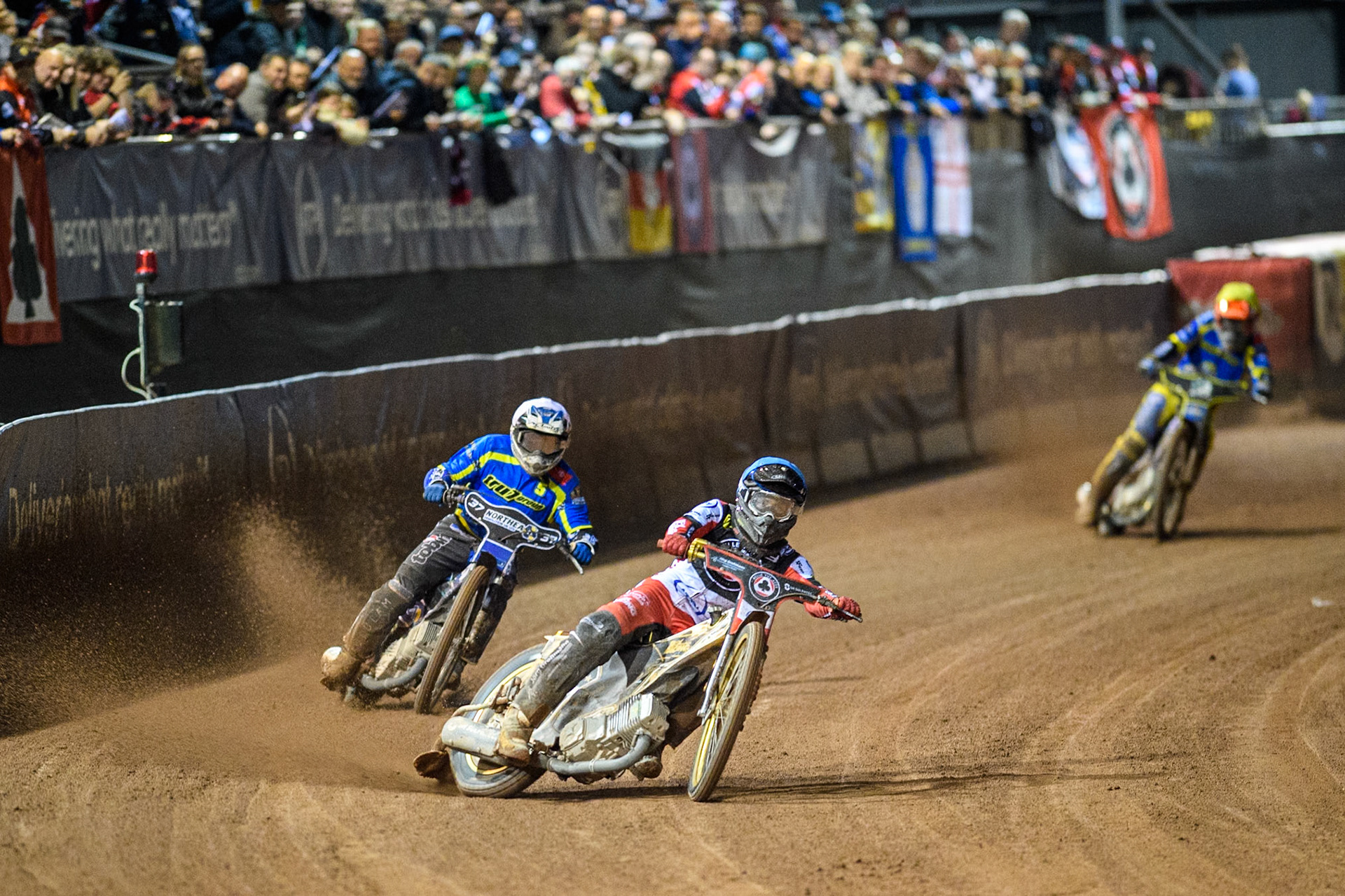 Belle Vue Aces' Norick Blodorn  in Blue leading Sheffield Tigers' Guest Rider Chris Harris  in White and Sheffield Tigers' Jason Edwards  in Yellow during the Rowe Motor Oil Premiership Play Off Semi Final 2, 1st Leg match between Belle Vue Aces and Sheffield Tigers at the National Speedway Stadium, Manchester on Monday 16th September 2024. (Photo: Ian Charles | MI News)