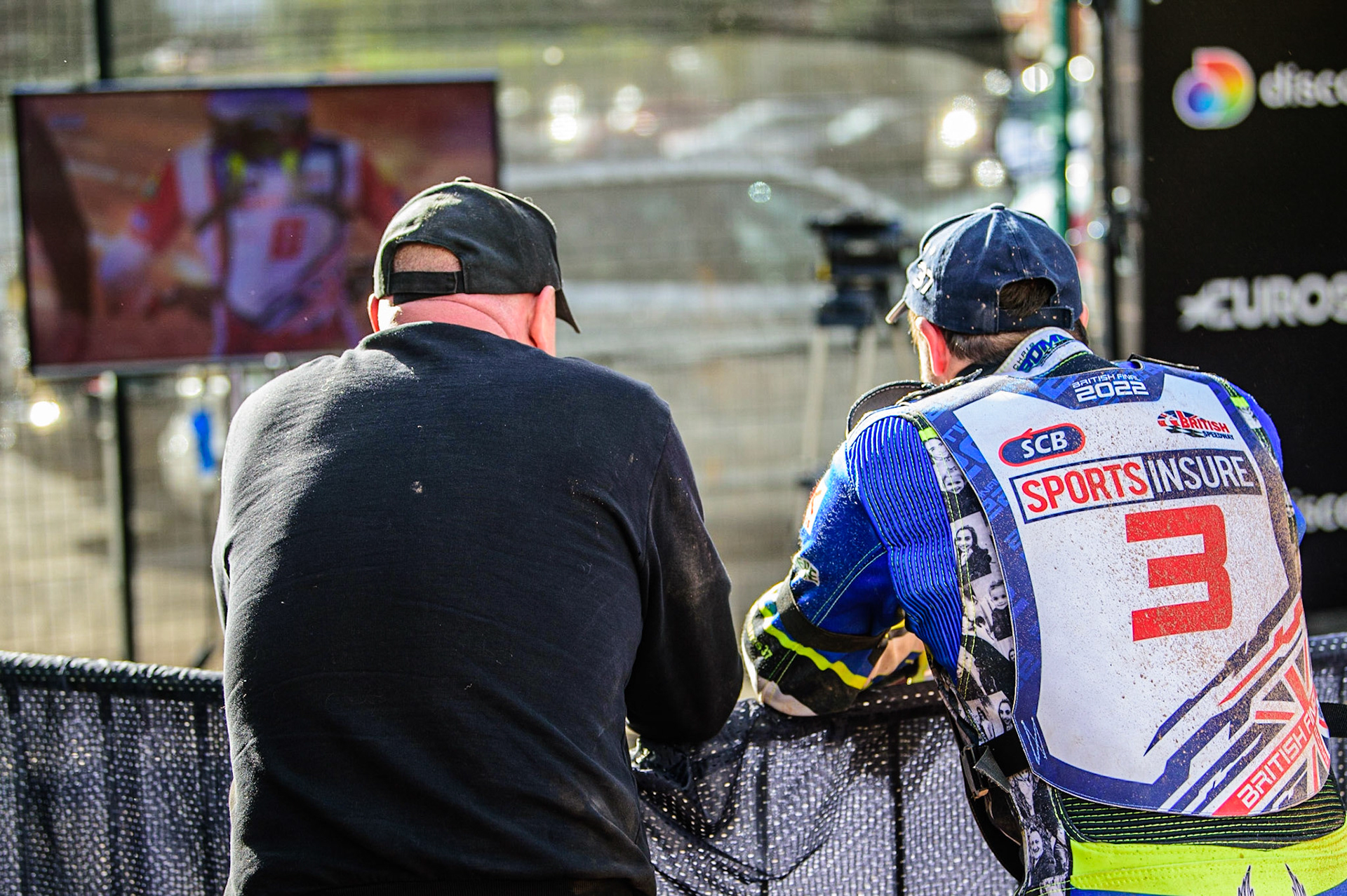 Chris Harris  (right) and his mechanic watch the Discovery coverage in the pits  during the Sports Insure British Speedway Final, at the National Speedway Stadium, Manchester, on Sunday 18th September 2022. (Credit: Ian Charles | MI News )