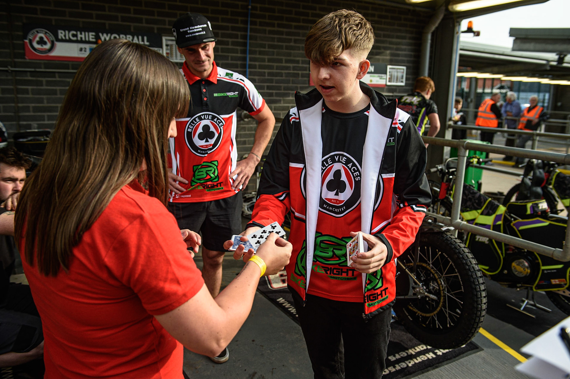 MANCHESTER UKClose up Magician Dan ‘The Magic Man’ Rhodes shows press officer Hayley Bromley a card trick under the gaze of Richie Worrall    during the SGB Premiership match between Belle Vue Aces and Ipswich Witches at the National Speedway Stadium, Manchester on Monday 2nd August 2021. (Credit: Ian Charles | MI News)