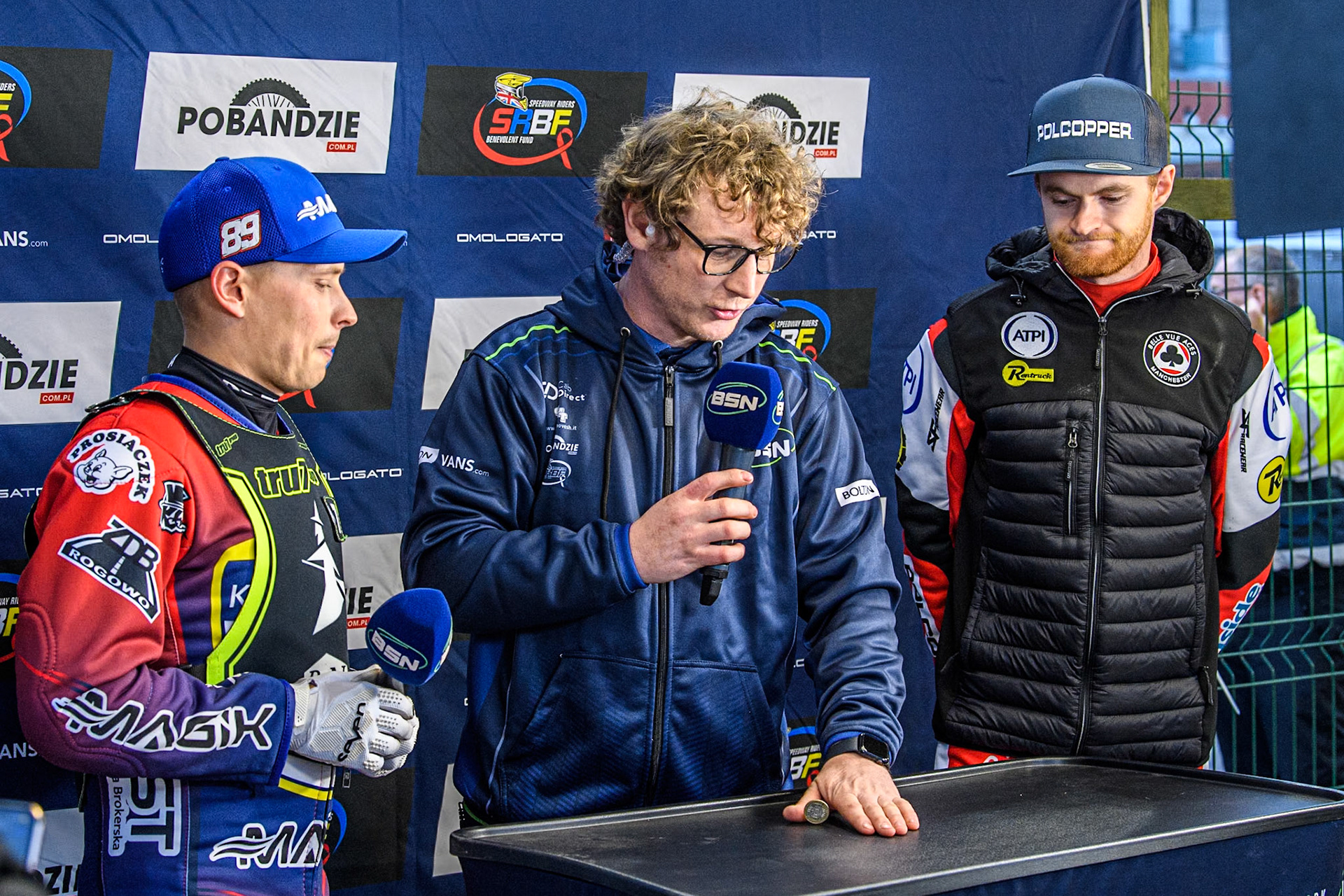 (L to R) Ipswich Witches' Emil Sayfutdinov, BSN Presenter Gregg Blair and Belle Vue Aces' Brady Kurtz as they do the toss up for gate positions in Heat 1 during the Rowe Motor Oil Premiership match between Belle Vue Aces and Ipswich Witches at the National Speedway Stadium, Manchester on Monday 22nd April 2024. (Photo: Ian Charles | MI News)