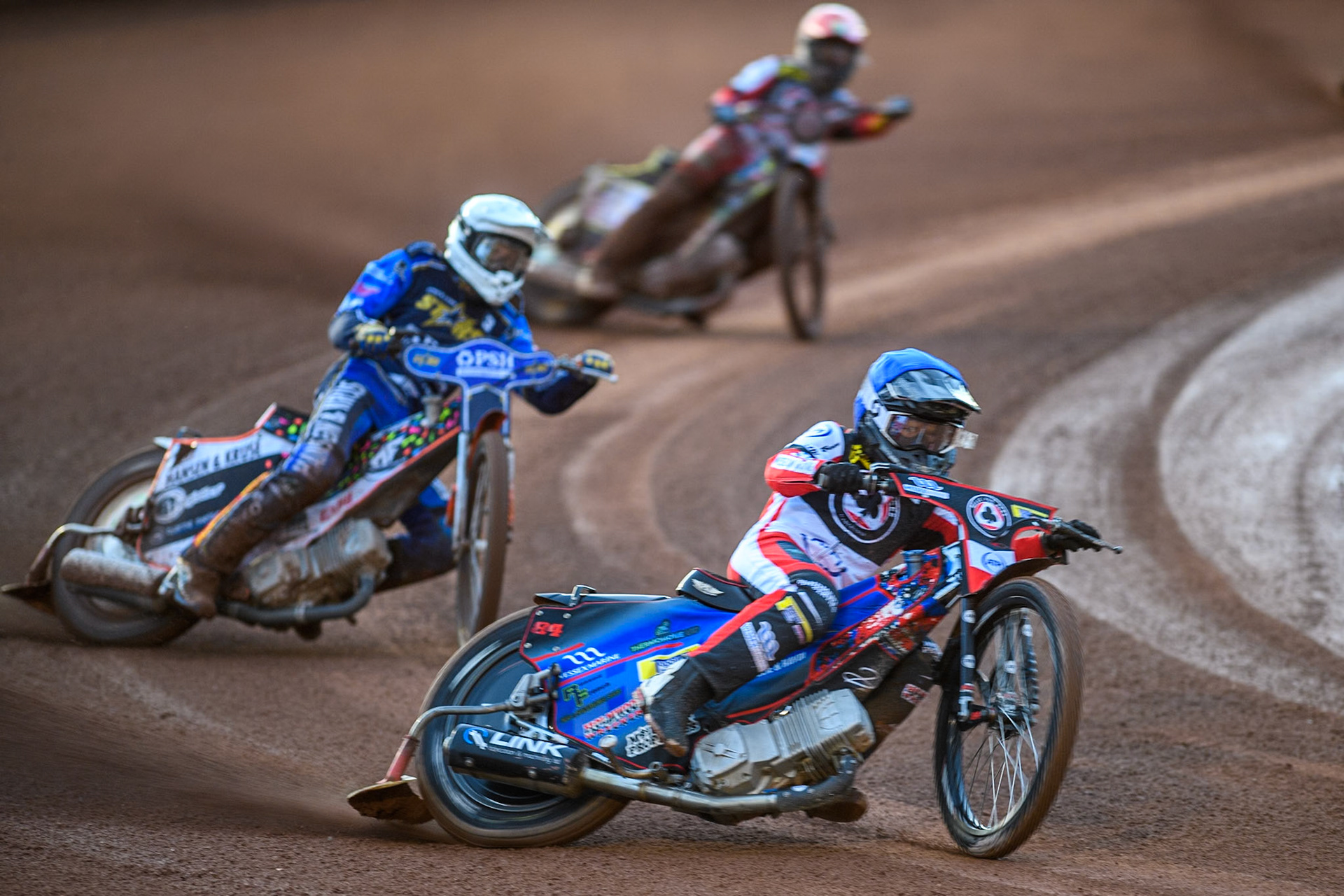 Belle Vue Aces' Ben Cook  in Blue leading Kings Lynn Stars' Niels-Kristian Iversen  in White and Belle Vue Aces' Jaimon Lidsey  in Red during the Rowe Motor Oil Premiership match between Belle Vue Aces and King's Lynn Stars at the National Speedway Stadium, Manchester on Monday 12th August 2024. (Photo: Ian Charles | MI News)
