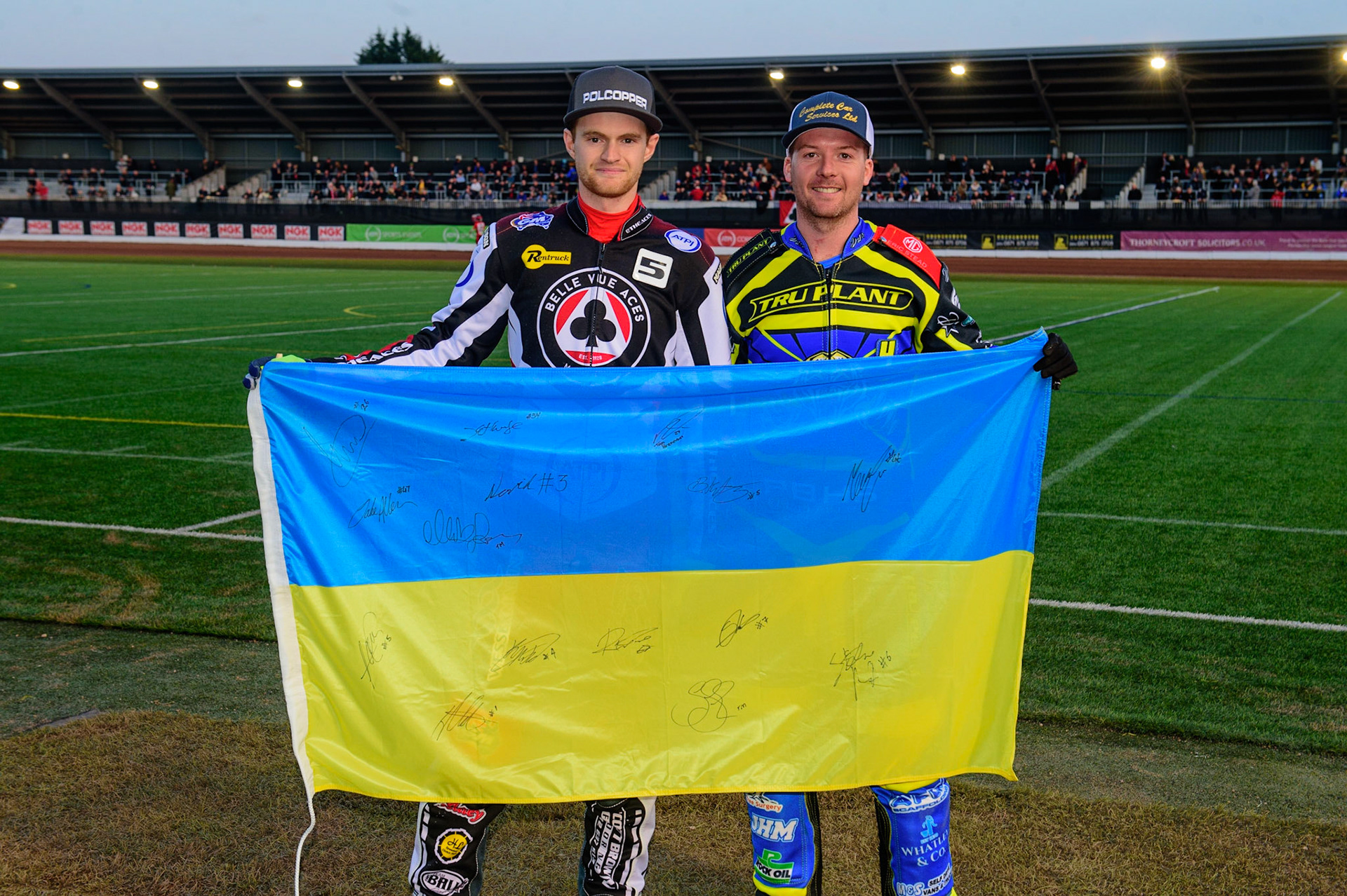 MANCHESTER, UK.  MAR 28TH. Brady Kurtz of Belle Vue  (left) and Kyle Howarth of Sheffield  with the Ukraine Flag. It was autographed by all the riders in the meeting, and will be auctioned for Ukrainian charities.  during the SGB Premiership League Cup match between Belle Vue Aces and Sheffield Tigers at the National Speedway Stadium, Manchester on Monday 28th March 2022. (Credit: Ian Charles | MI News)