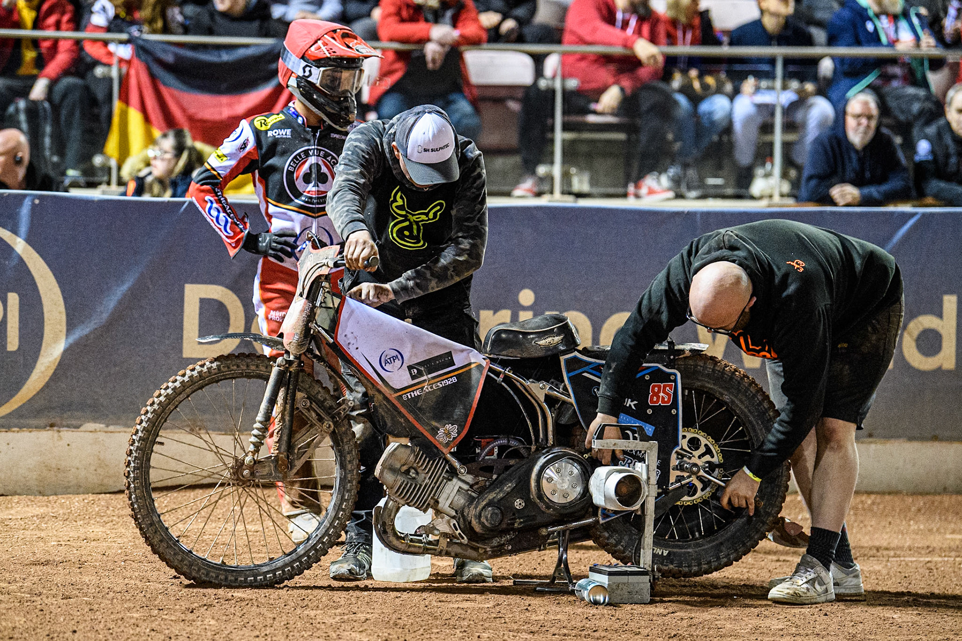Mechanics work on Zach Cook of Belle Vue Aces’ bike iwhilst waiting for the run of a heat during the Rowe Motor Oil Premiership match between Belle Vue Aces and King's Lynn Stars at the National Speedway Stadium, Manchester on Monday 5th April 2025. (Photo: Ian Charles | MI News)