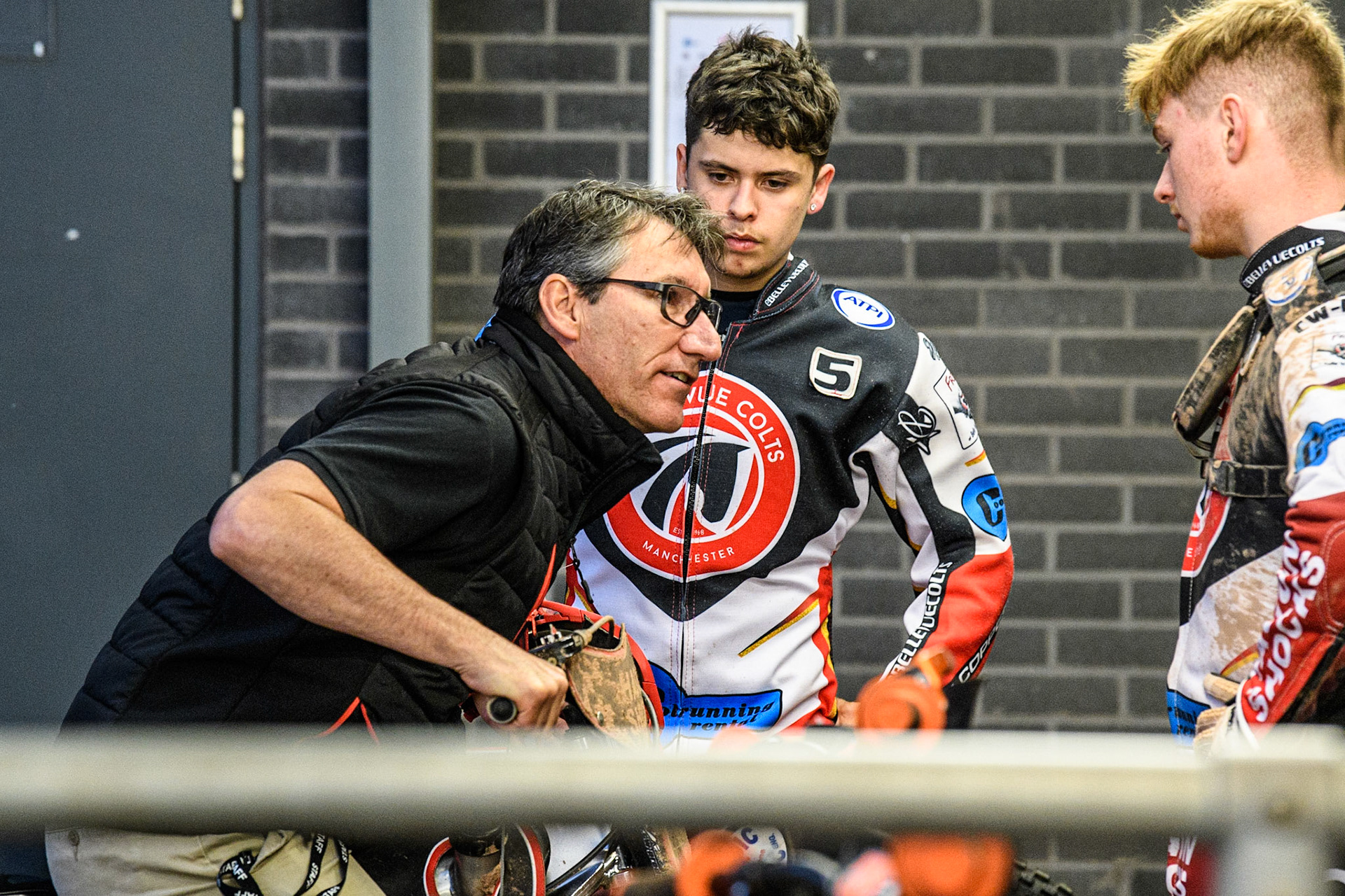 Belle Vue CEO Mark Lemon (left) demonstrates to James Pearson (Centre) and Sam Hagon (right) during the National Development League match between Belle Vue Colts and Mildenhall Fens Tigers at the National Speedway Stadium, Manchester on Friday 26th May 2023. (Photo: Ian Charles | MI News)