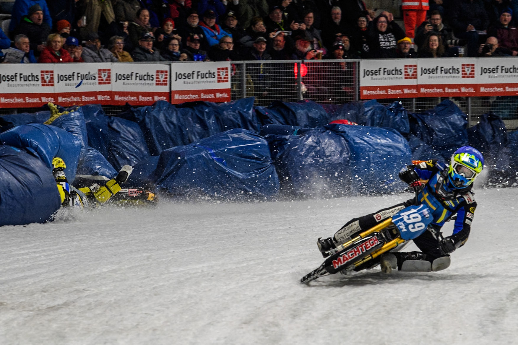 Sweden's Martin Haarahiltunen (199)  (Blue) leads  and Germany's Markus Jell (82) (Red) and Finland's Heikki Huusko (67)y\ collide and crash into the bales during the FIM Ice Speedway Gladiators World Championship Final 2 at the Max-Aicher-Arena, Inzell on Sunday 24 March 2024. (Photo: Ian Charles | MI News)