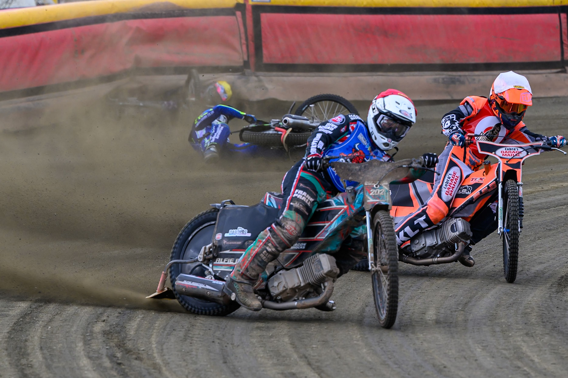 Alfie Bowtell of Buxton Bulls  in Red Connor Coles of NDL Nomads in White as Sam Woods of NDL Nomads  slides into the safety fence as Arran Butcher of Buxton Bulls  spins his machine during the  Challenge match between Buxton Bulls and NDL Nomads at Hi-Edge Speedway, Buxton on Sunday 19th April 2026. (Photo: Ian Charles | MI News)