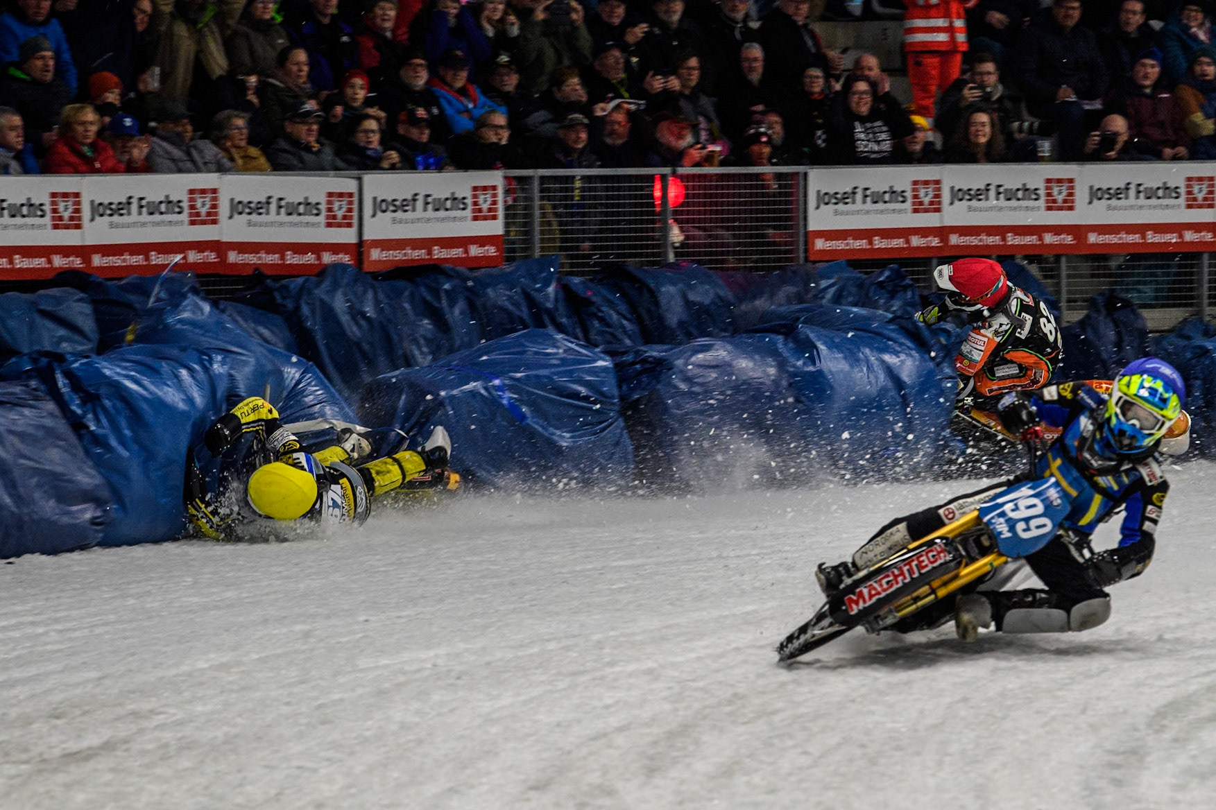 Sweden's Martin Haarahiltunen (199)  (Blue) leads  and Germany's Markus Jell (82) (Red) and Finland's Heikki Huusko (67)y\ collide and crash into the bales during the FIM Ice Speedway Gladiators World Championship Final 2 at the Max-Aicher-Arena, Inzell on Sunday 24 March 2024. (Photo: Ian Charles | MI News)