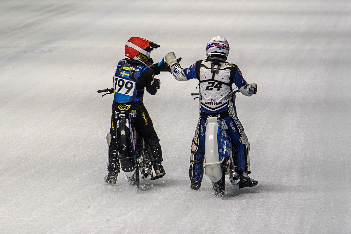 Max Koivula (24) of Finland in White congratulates Martin Haarahiltunen (199) of Sweden on his heat win during the Ice  Speedway Gladiators World Championship Final 1 at Max-Aicher-Arena, Inzell on Saturday 15th March 2025. (Photo: Ian Charles | MI News)