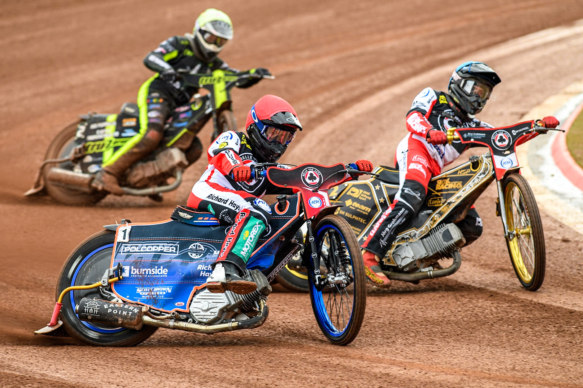 Belle Vue Aces' Brady Kurtz  in Red and team mate Belle Vue Aces' Norick Blodorn  in Blue leading Ipswich Witches' Guest Rider Tom Brennan  in White during the Rowe Motor Oil Premiership match between Belle Vue Aces and Ipswich Witches at the National Speedway Stadium, Manchester on Monday 1st July 2024. (Photo: Ian Charles | MI News)
