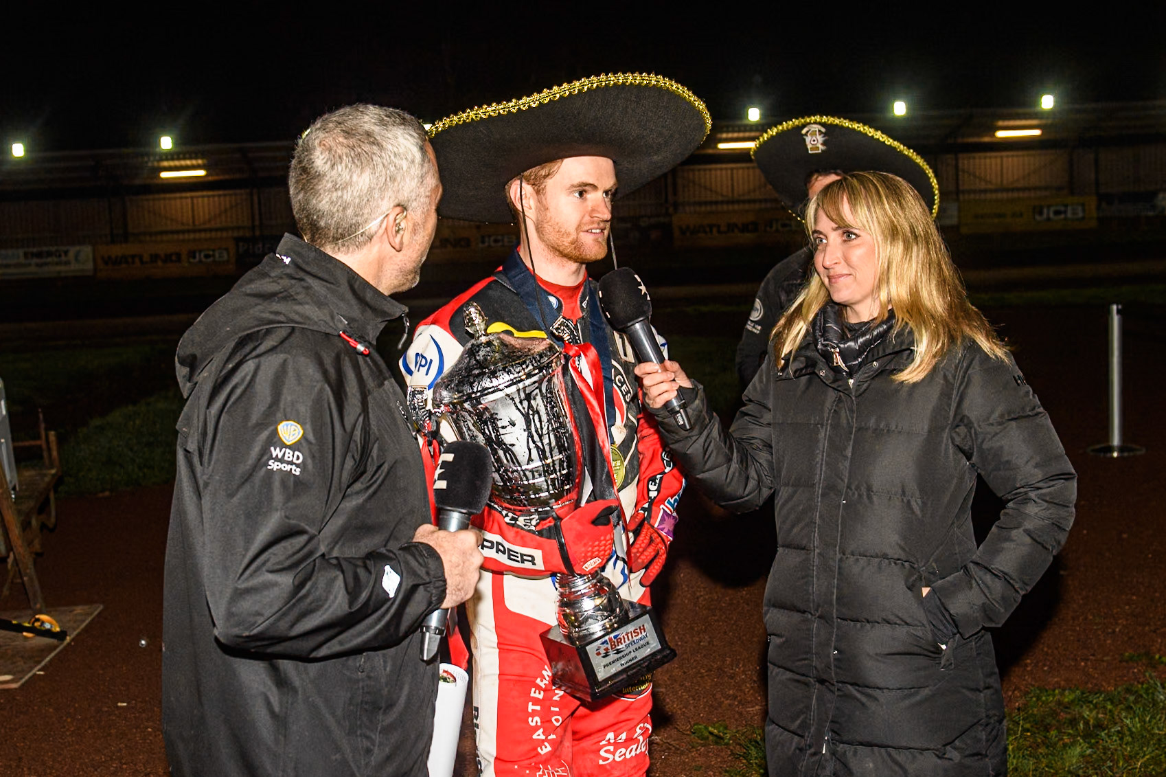 Belle Vue Aces' Brady Kurtz centre gives an interview to (Left) Scott Nicholls and (Right) Kiri Bloore during the Rowe Motor Oil Premiership Grand Final 2nd Leg between Leicester Lions and Belle Vue Aces at the Pidcock Motorcycles Arena, Leicester on Thursday 26th September 2024. (Photo: Ian Charles | MI News)
