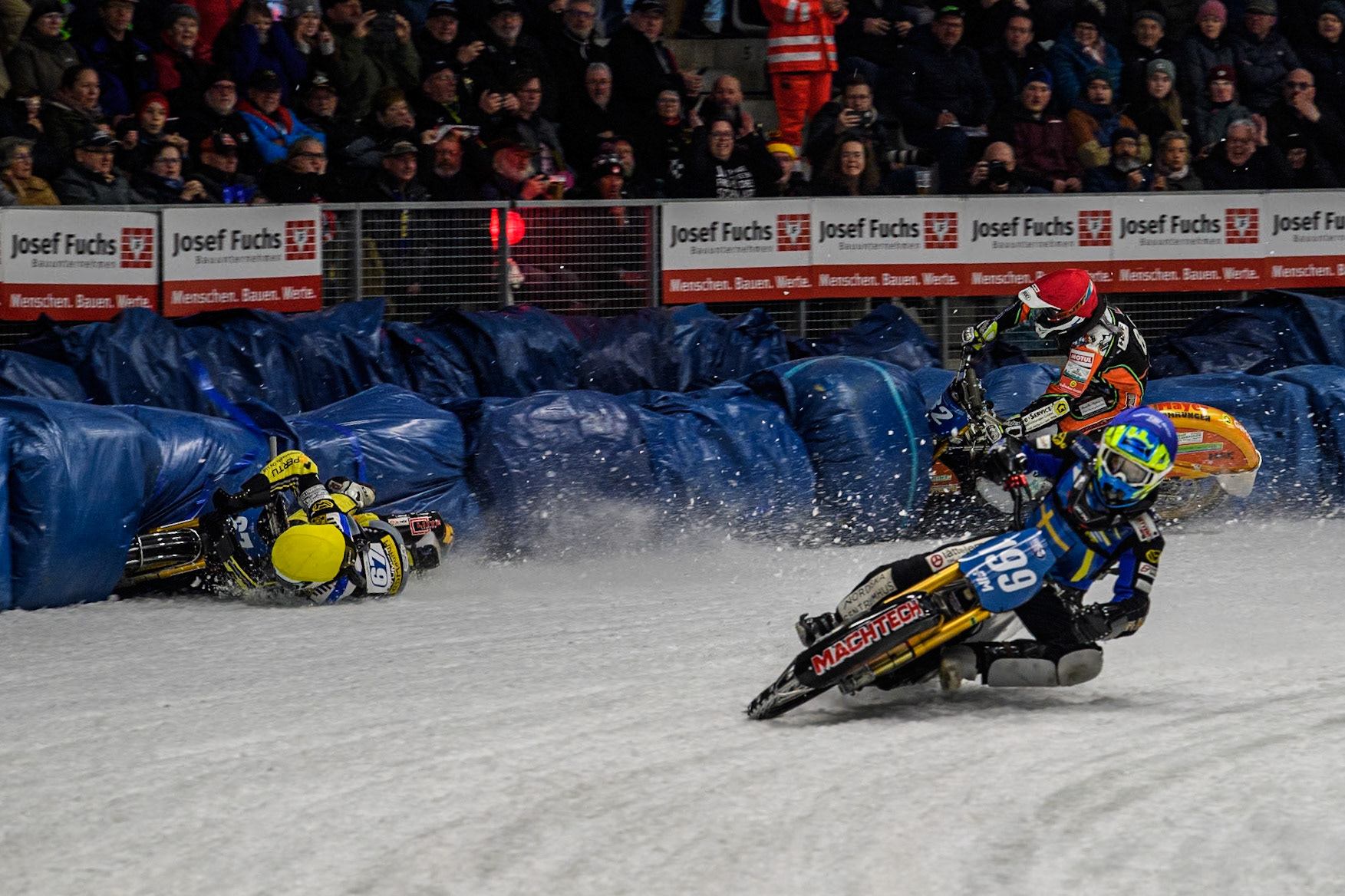 Sweden's Martin Haarahiltunen (199)  (Blue) leads  and Germany's Markus Jell (82) (Red) and Finland's Heikki Huusko (67)y\ collide and crash into the bales during the FIM Ice Speedway Gladiators World Championship Final 2 at the Max-Aicher-Arena, Inzell on Sunday 24 March 2024. (Photo: Ian Charles | MI News)