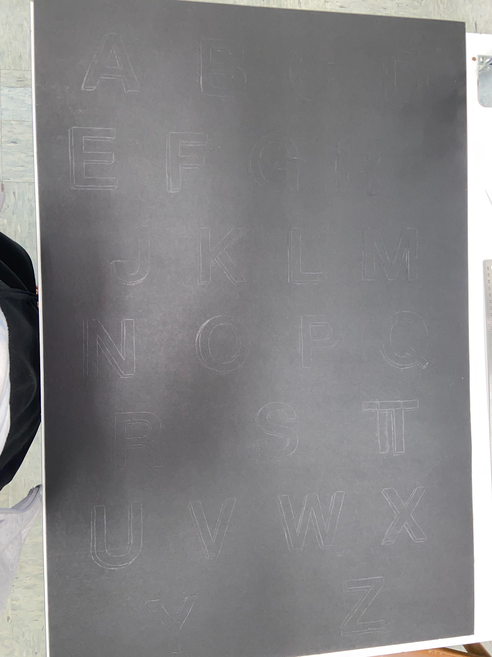 Drawn out alphabet on black mat board