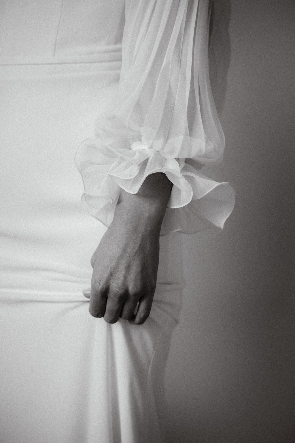 Fotografia di Arianna Macherelli, specializzata in Fotografia di Matrimonio, dettaglio in bianco e nero della mano della sposa che si sorregge l'abito