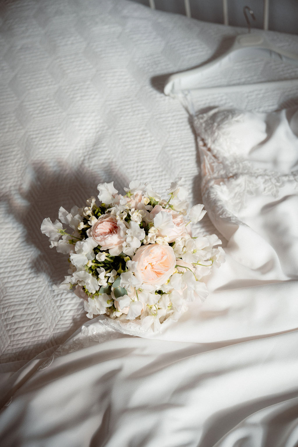 Fotografia di Arianna Macherelli, specializzata in Fotografia di Matrimonio, dettaglio del bouquet accanto all'abito da sposa steso sul letto