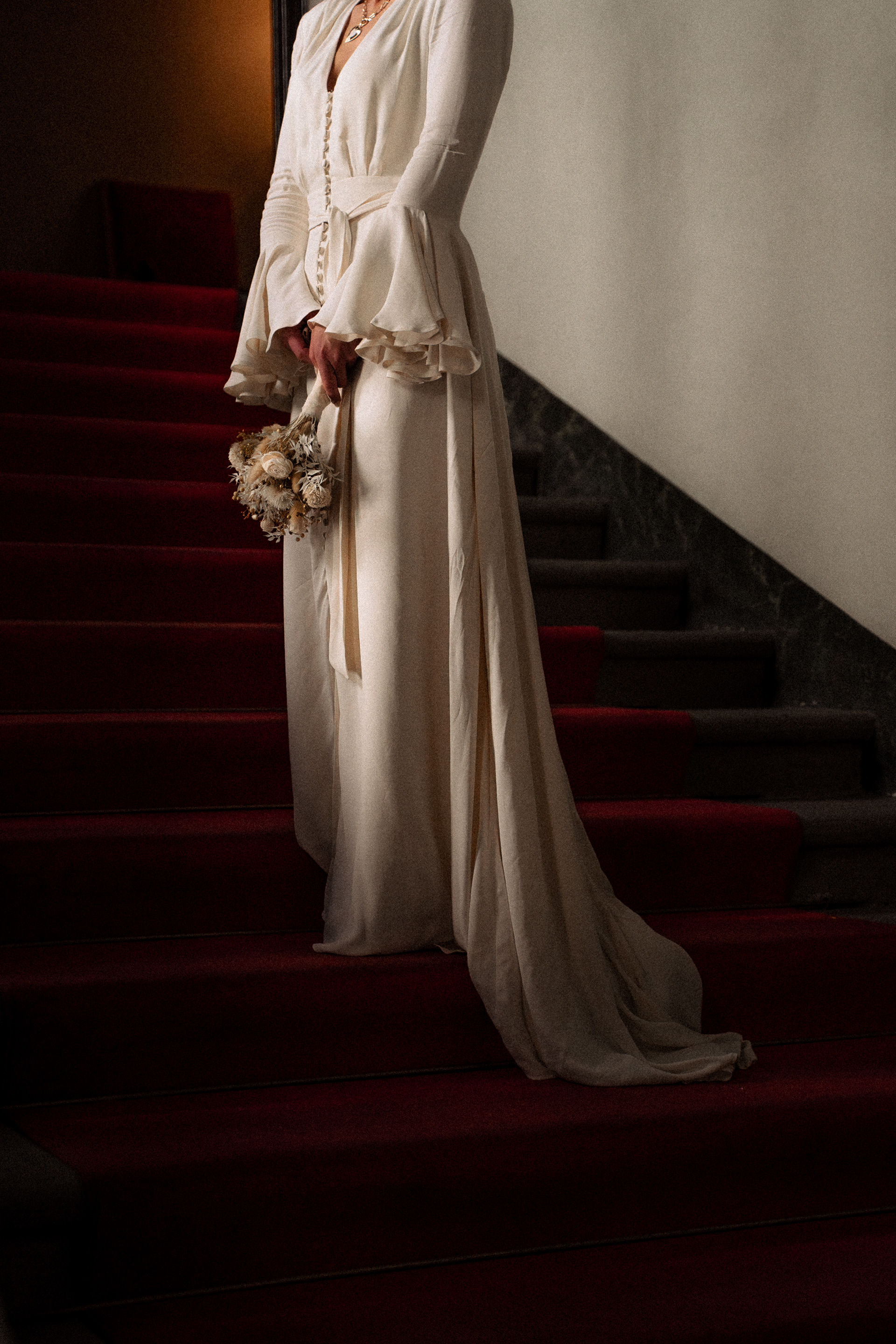 Fotografia di Arianna Macherelli, specializzata in Fotografia di Matrimonio, dettaglio dell'abito della sposa con in mano il bouquet