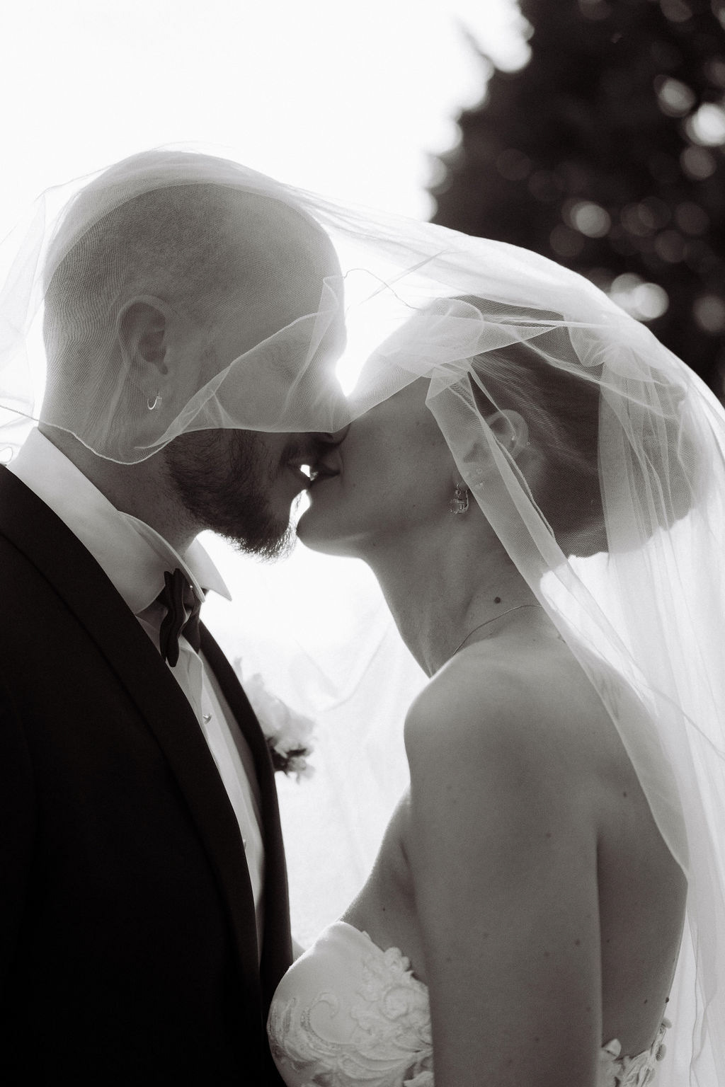 Fotografia di Arianna Macherelli, specializzata in Fotografia di Matrimonio, ritratto in bianco e nero del bacio tra gli sposi sotto il velo