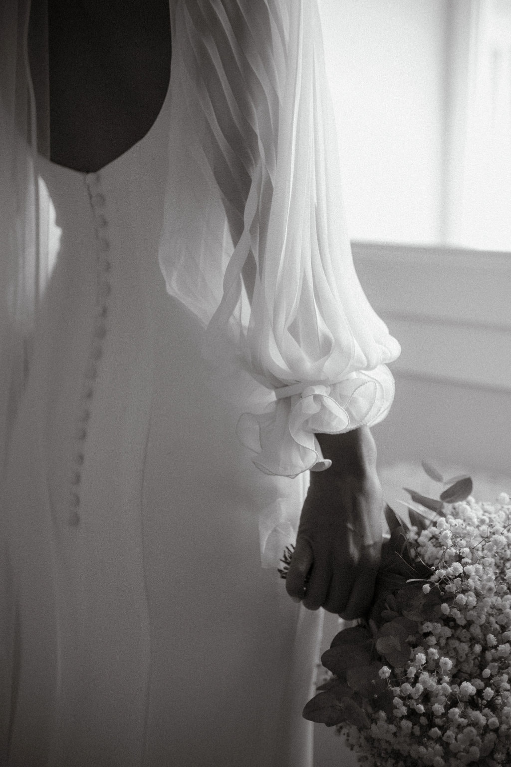 Fotografia di Arianna Macherelli, specializzata in Fotografia di Matrimonio, dettaglio in bianco e nero dell'abito della sposa con il bouquet