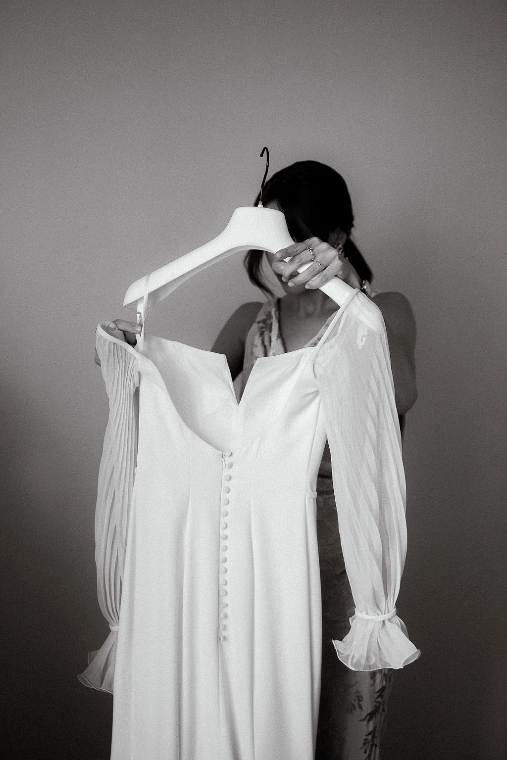 Fotografia di Arianna Macherelli, specializzata in Fotografia di Matrimonio, dettaglio in bianco e nero della Testimone della sposa che le sorregge l'abito