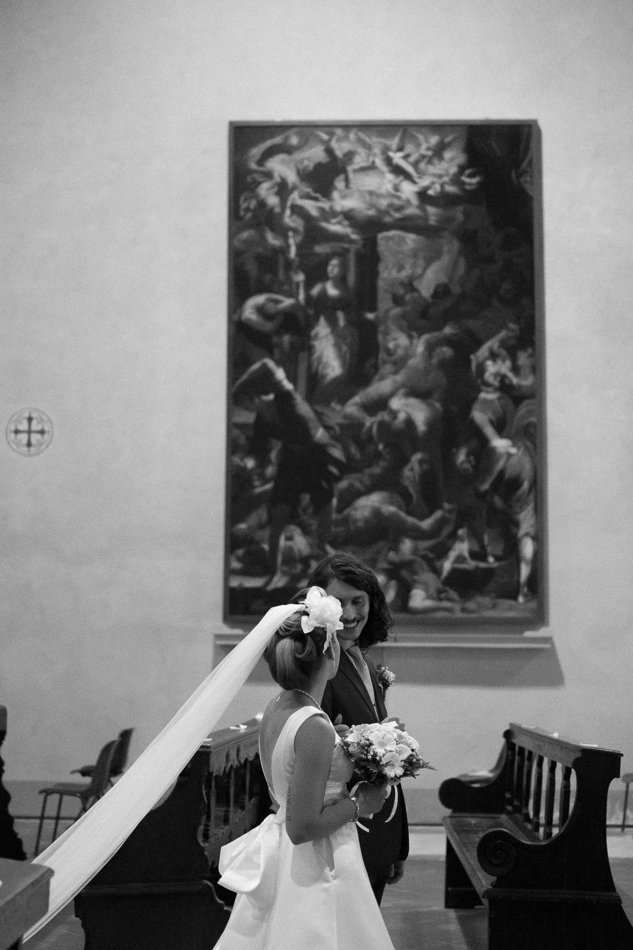Fotografia di Arianna Macherelli, specializzata in Fotografia di Matrimonio, immagine in bianco e nero della camminata mano nella mano degli sposi in mezzo alla navata della chiesa