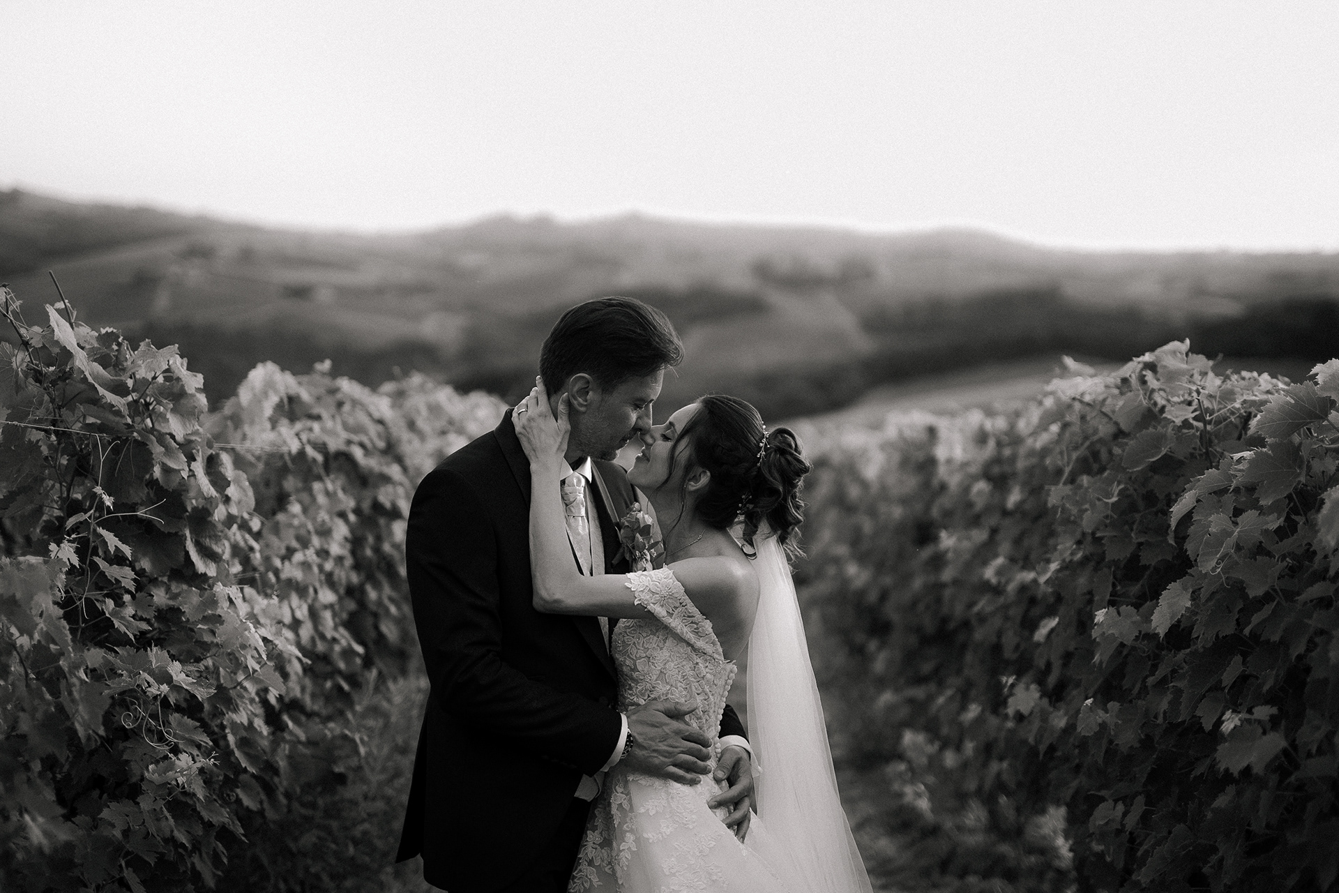Fotografia di Arianna Macherelli, specializzata in Fotografia di Matrimonio, due sposi che si baciano immersi nelle vigne toscane