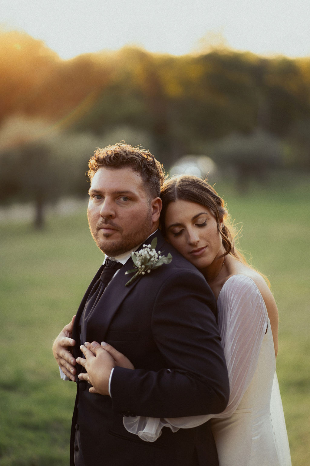 Fotografia di Arianna Macherelli, specializzata in Fotografia di Matrimonio, ritratto dello sposo che guarda in camera con la sposa con gli occhi chiusa appoggiata alla sua schiena