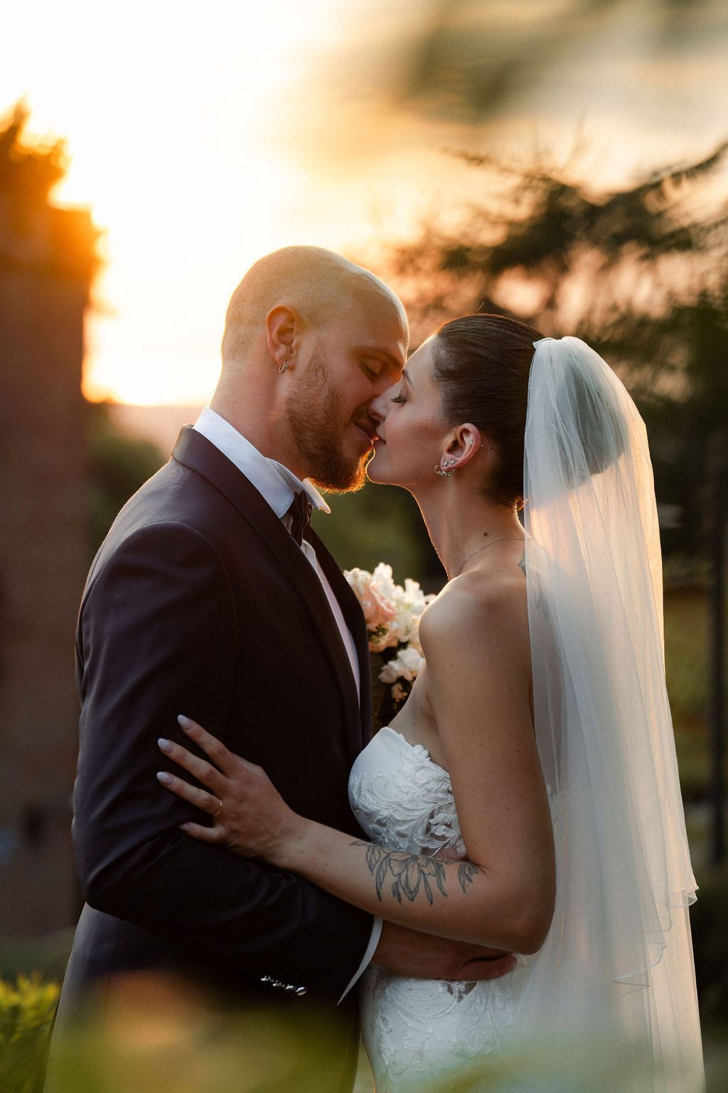 Fotografia di Arianna Macherelli, specializzata in Fotografia di Matrimonio, ritratto del bacio tra gli sposi all'ora del tramonto in controluce