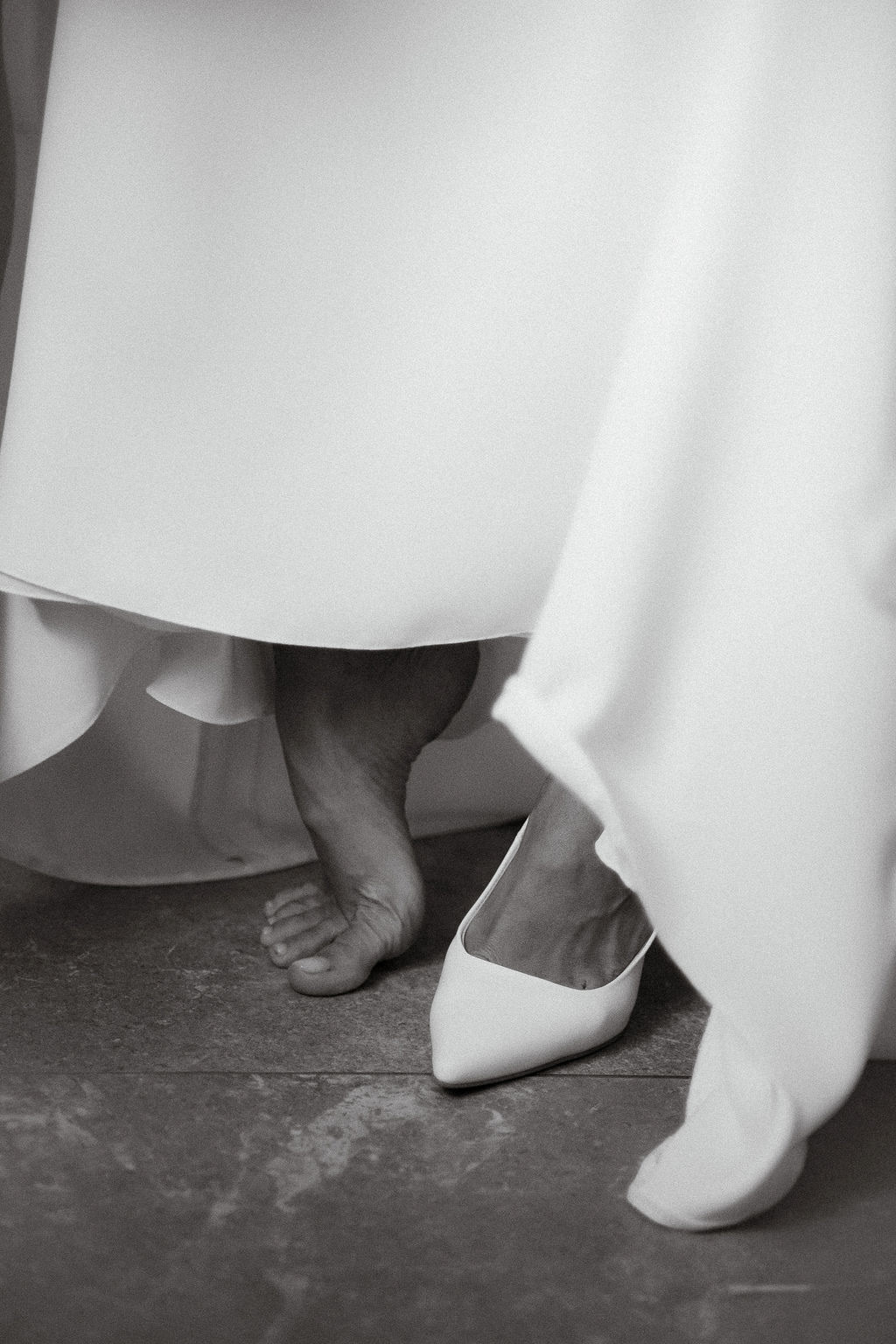 Fotografia di Arianna Macherelli, specializzata in Fotografia di Matrimonio, dettaglio in bianco e nero di reportage con un piede senza tacco di una sposa in preparazione