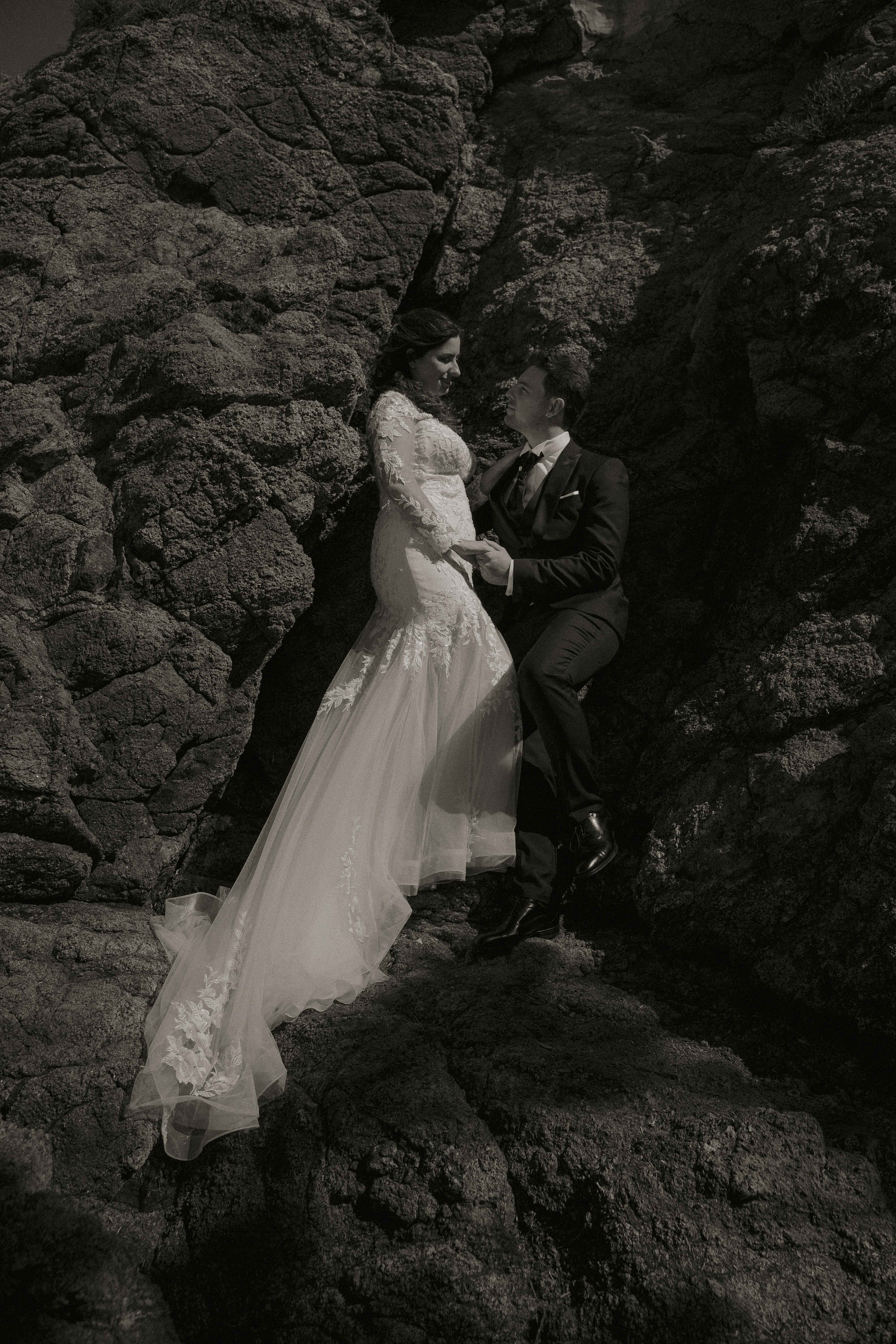 Fotografia di Arianna Macherelli, specializzata in Fotografia di Matrimonio, ritratto di coppia in bianco e nero degli sposi che si guardano appoggiati a delle rocce
