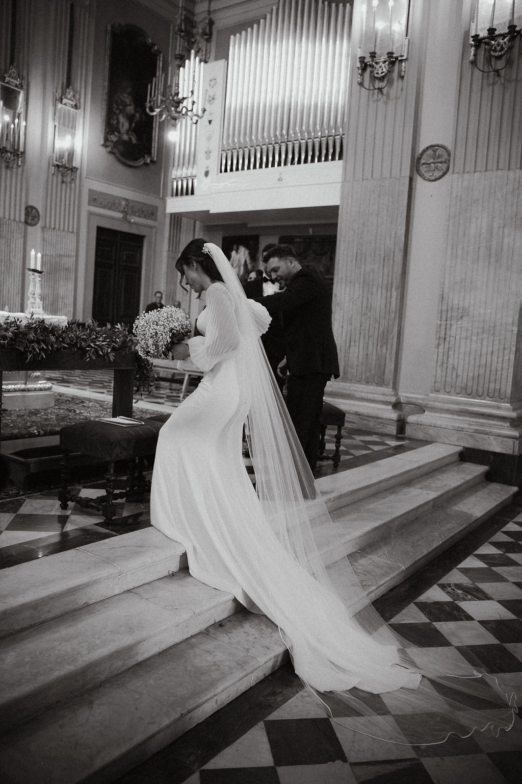 Fotografia di Arianna Macherelli, specializzata in Fotografia di Matrimonio, fotografia di reportage in bianco e nero che cammina sulle scale dell'altare della Chiesa