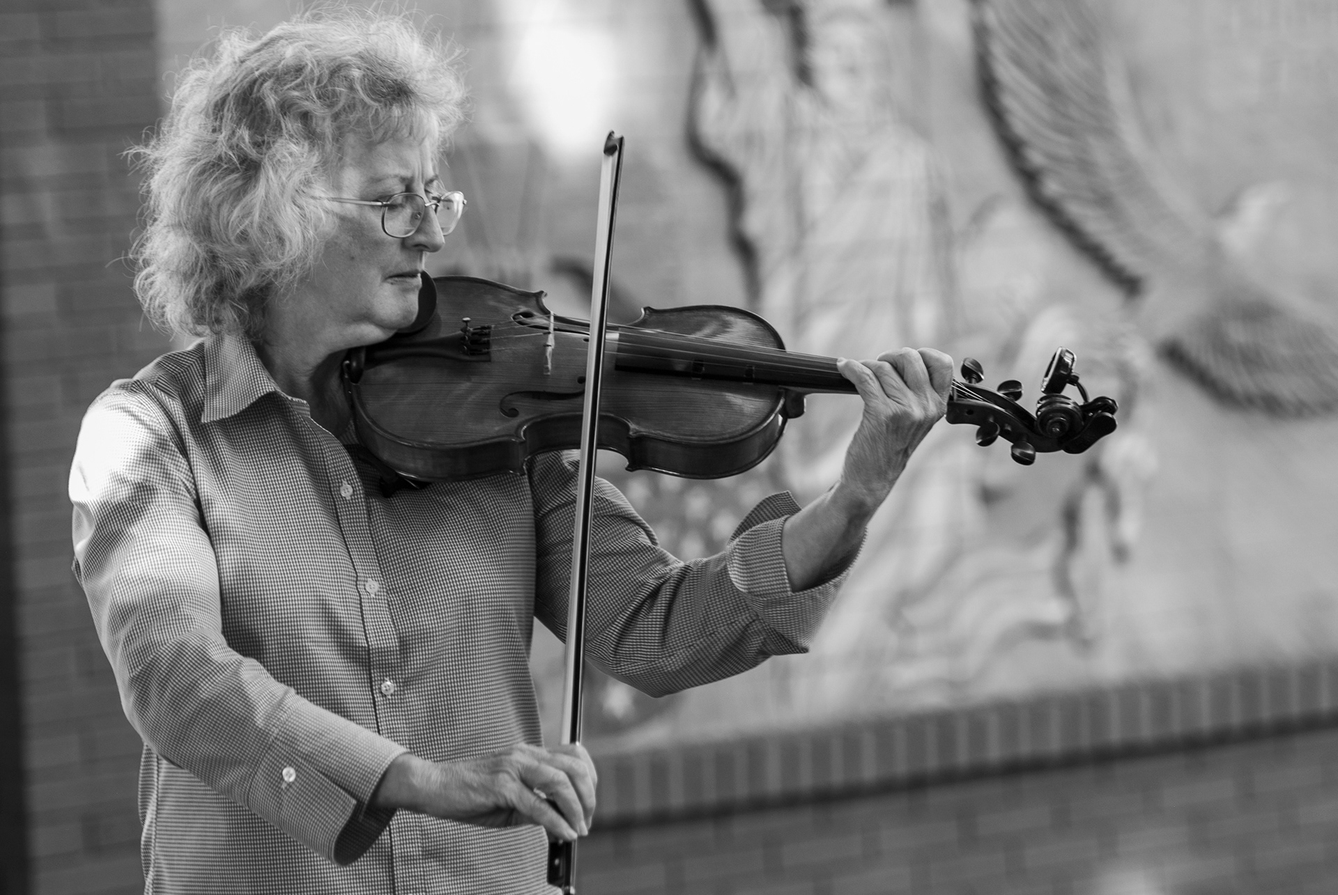 Kay Lorson warms up her violin under the shade of the trees on the Mount Vernon Public Square.