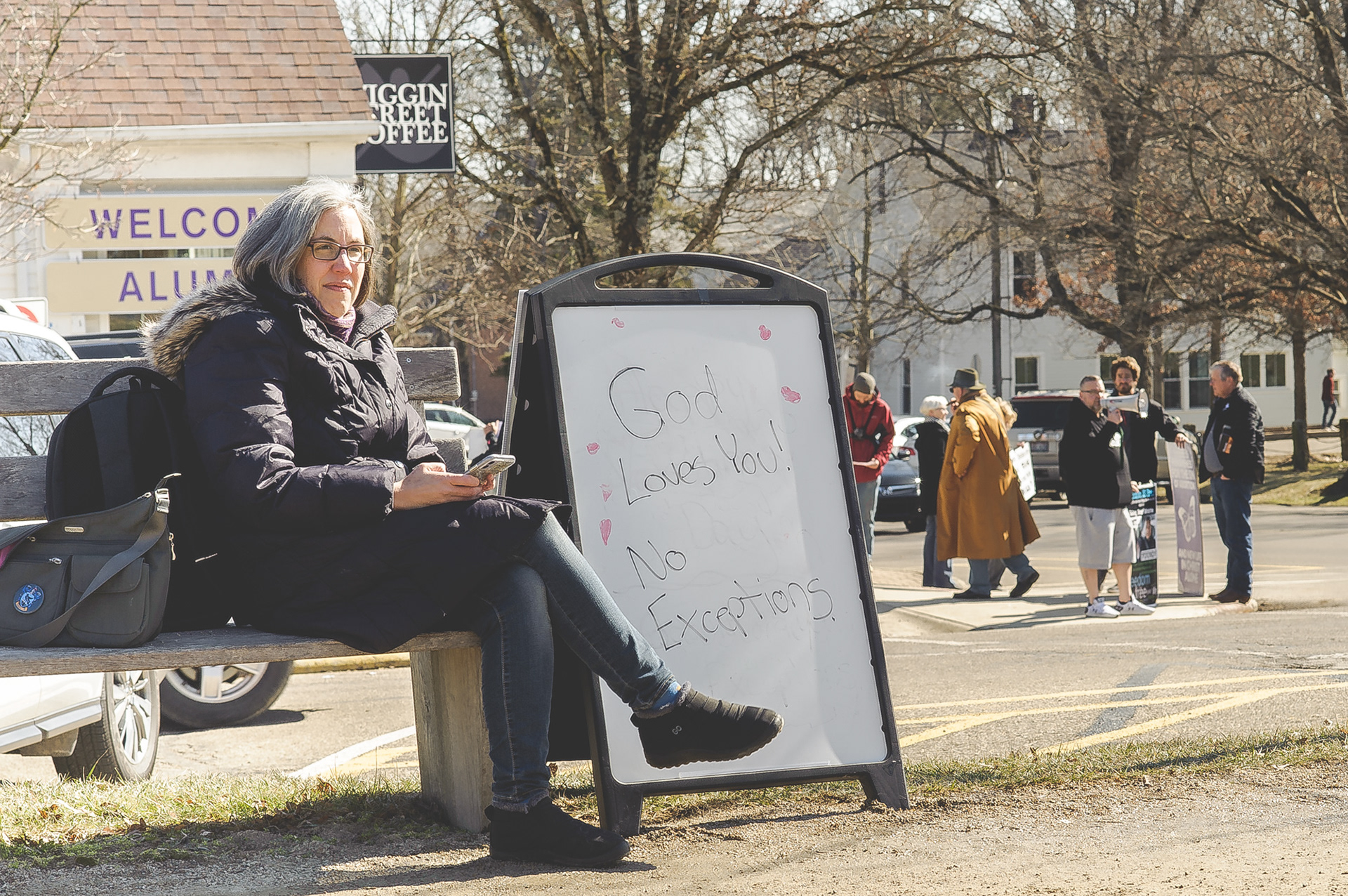 Harcourt Parish Episcopal Priest Rachel Kessler, left, sits by a whiteboard in Gambier February 22, 2020 as religious protesters gathered behind her, on the corner of Gaskin Avenue and Wiggin Street. The protest was mounted against a children’s storytime program dealing with transgender acceptance and understanding at Gund Gallery. Protesters did engage with students and those visiting the village, but it was relatively peaceful.
