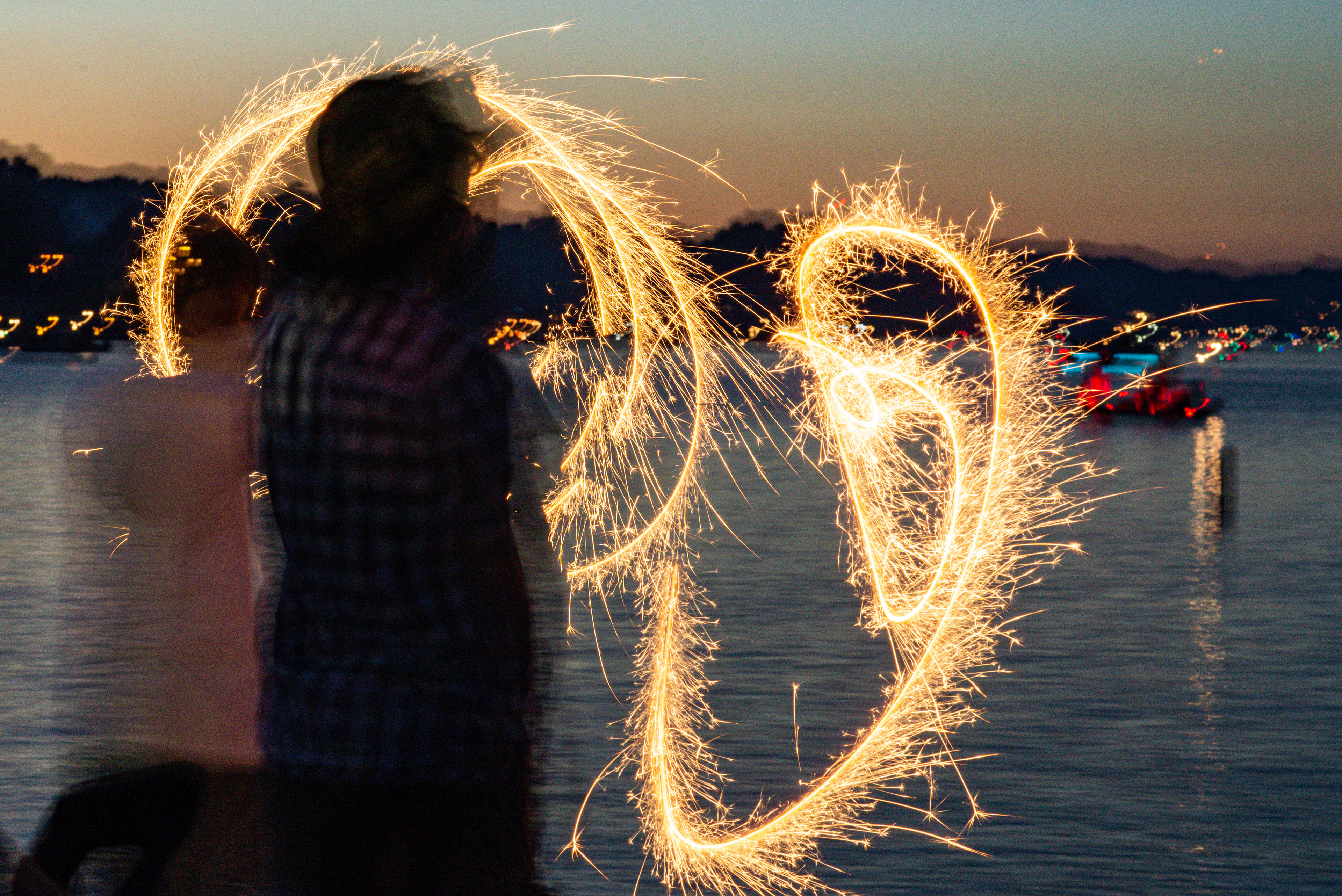 A youngster plays with a sparkler on the shore of Apple Valley Lake.