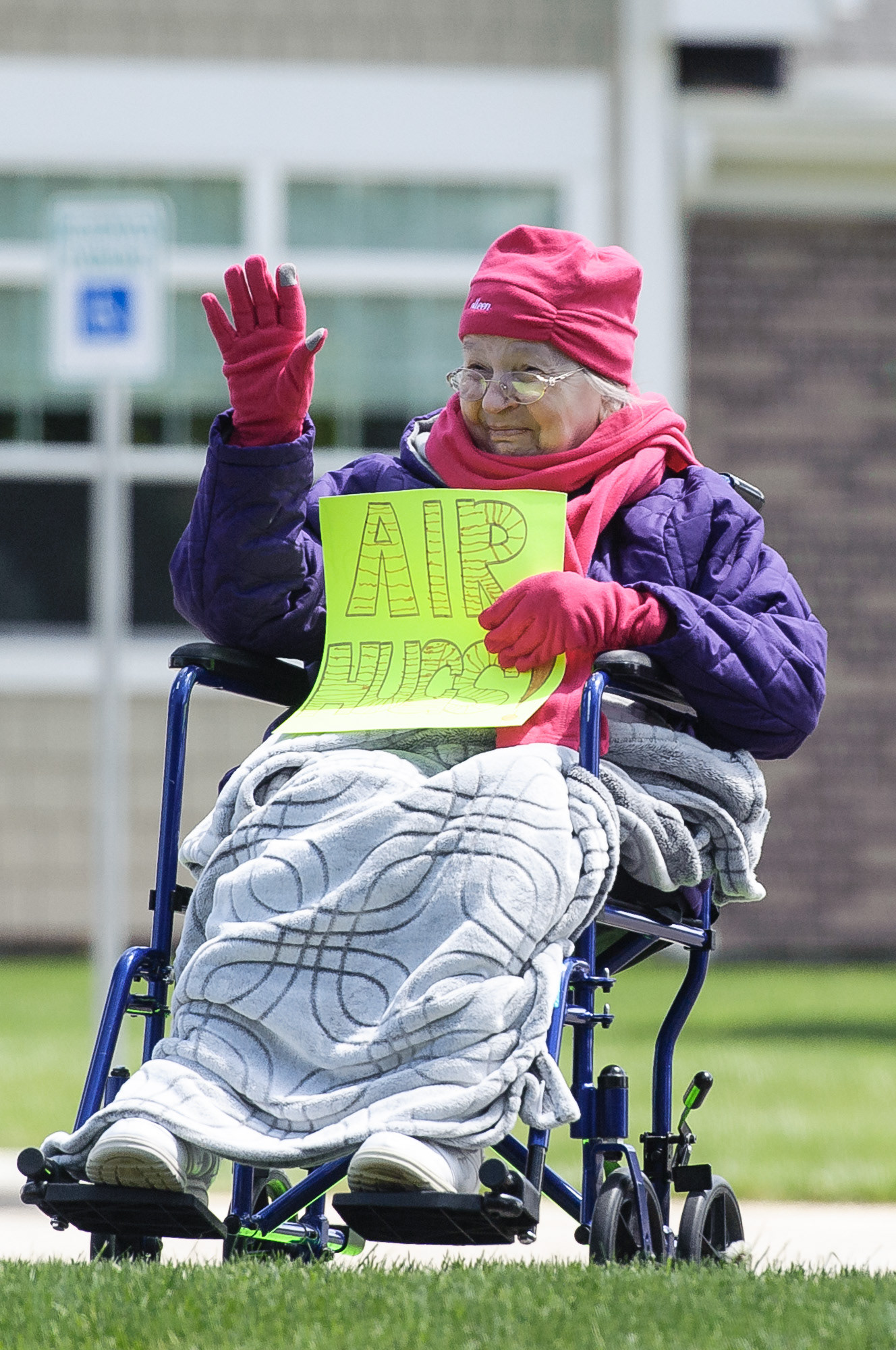 Colleen Brokaw waves while holding an “Air Hugs” signs during the May 6, 2020 parade at the Ohio Eastern Star Home in Mount Vernon. Members of the community, family and staff participate each day at 2 p.m. as a parade circles the Eastern Star campus twice.