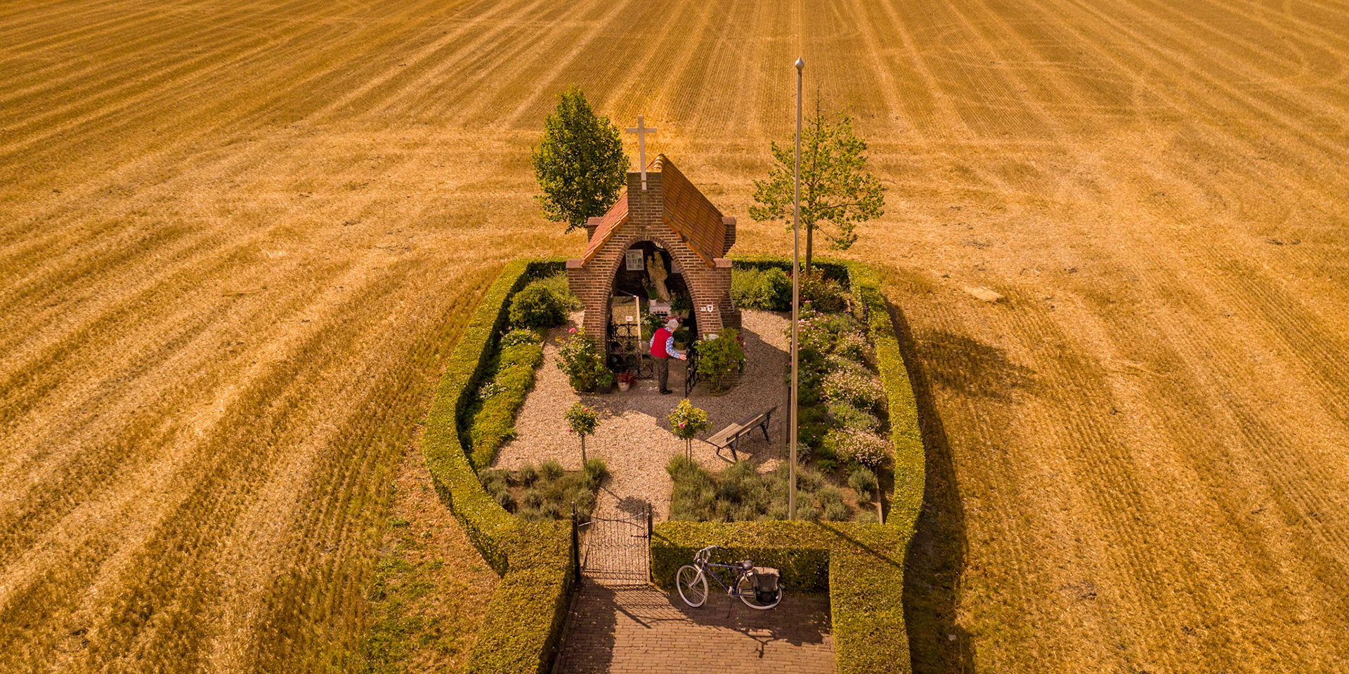 Chapel with old man in the middle of a grain field