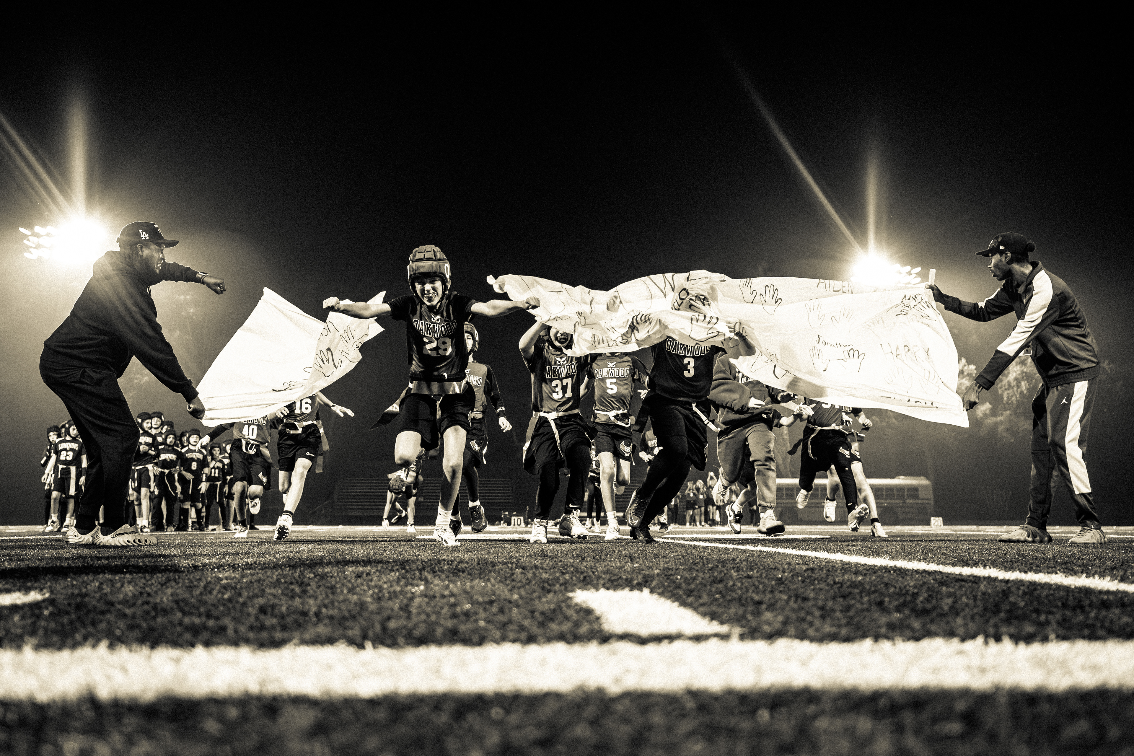 Oakwood elementary flag football players break through a banner before a flag football game in Studio City, CA