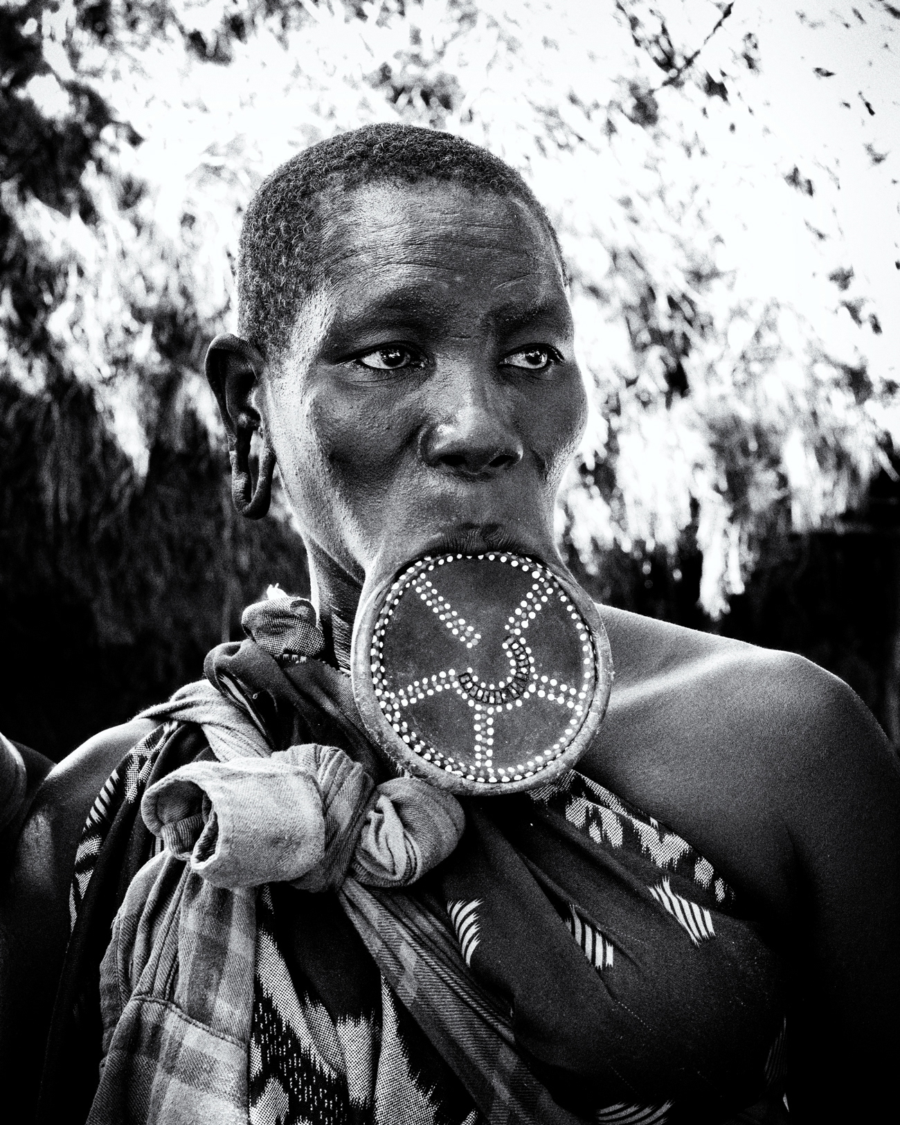 Black and white portrait of a woman from the Mursi community wearing a traditional lip plate, Lower Omo Valley, Ethiopia, 2025.