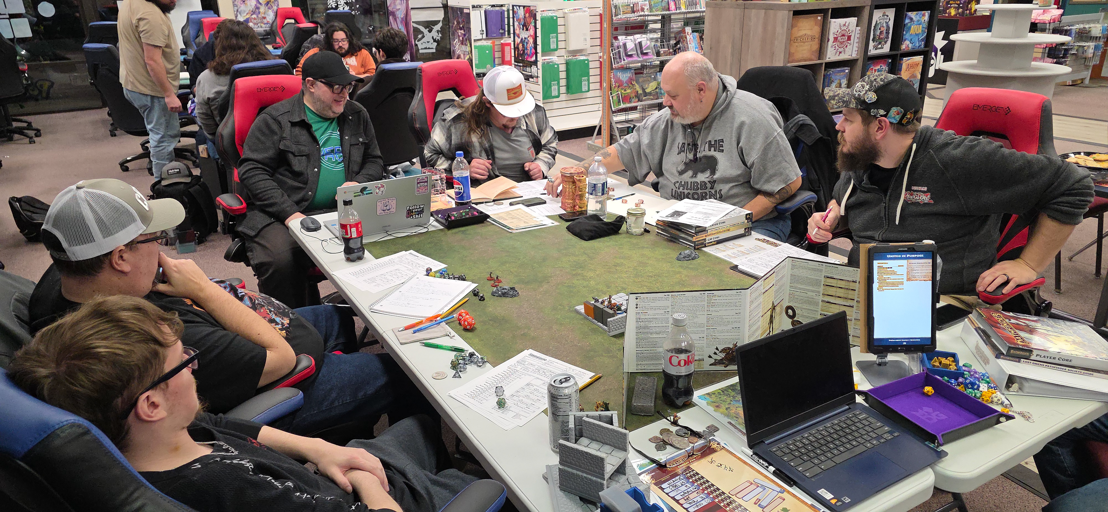 That guy with his hat tipped down is the rogue, and he's new to RPG's. He plays a halfling rogue, but he plays it like a kender. We refer to him as "the kender". They're probably helping him figure out sneak attack damage. 
