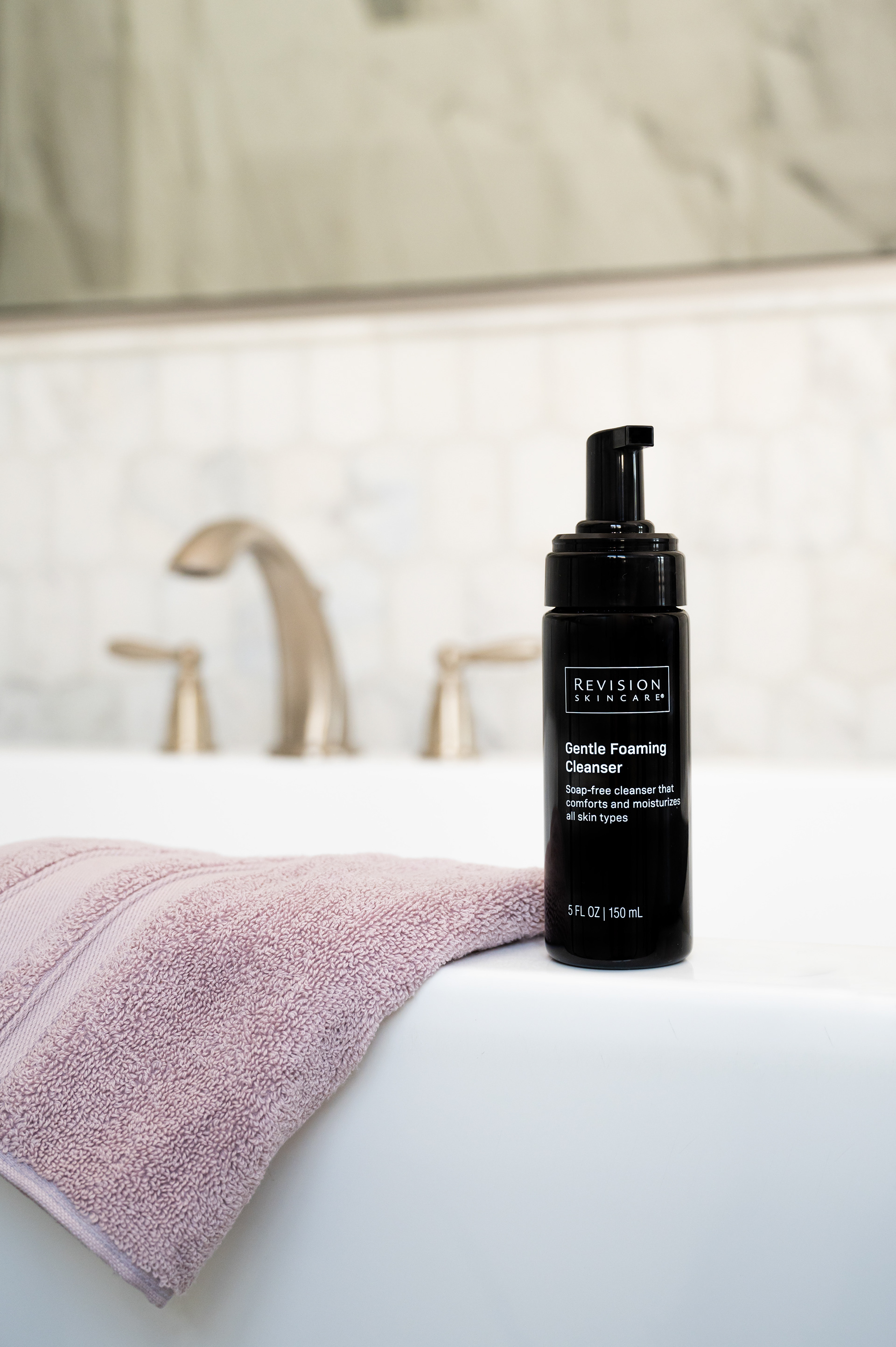 Revision Skincare Gentle foaming Cleanser styled at the edge of a bathtub with a pink towel