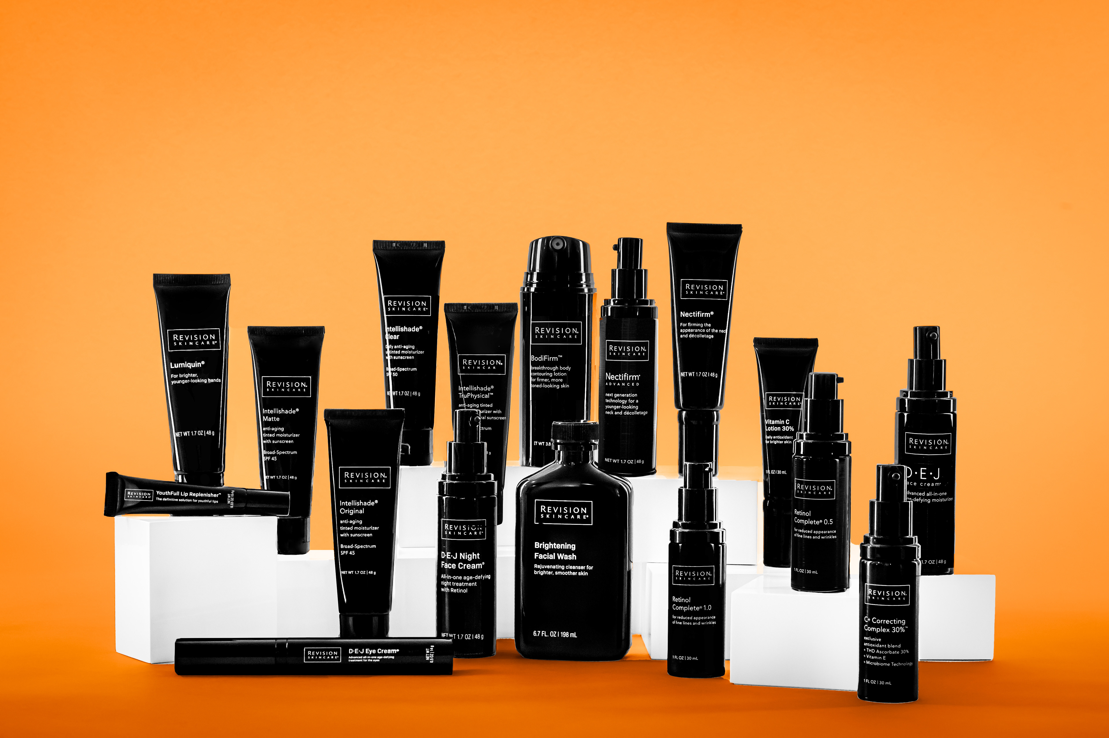 Revision Skincare product line styled on white blocks with an orange background