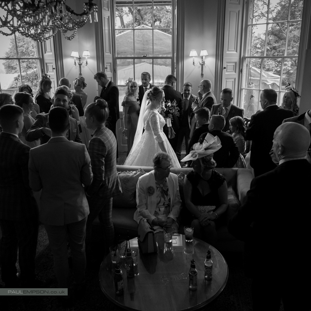 Middleton Lodge Wedding bride in her white dress stands sunlit amongst her guests