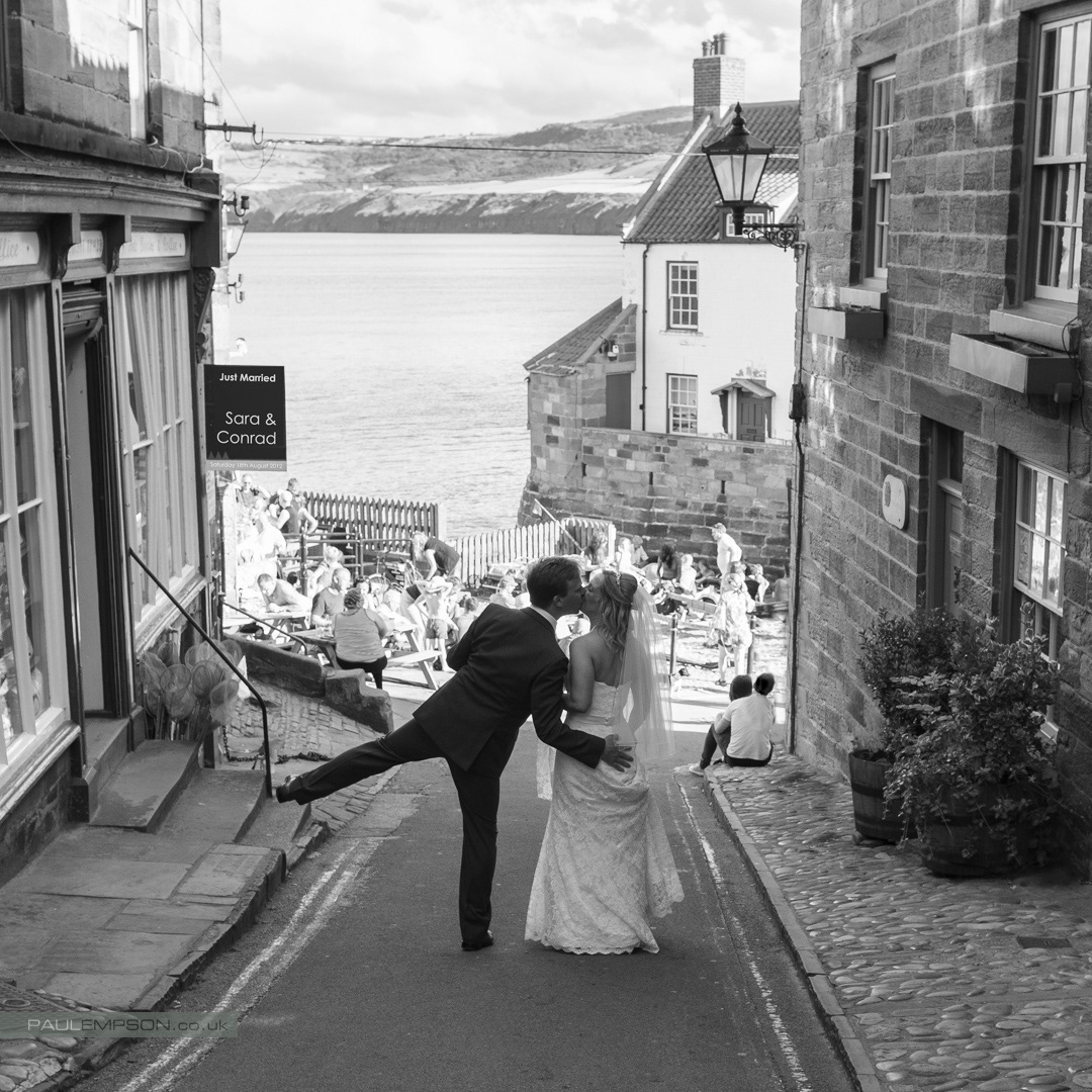 Robin Hoods Bay wedding the bride & groom, kiss, in the street