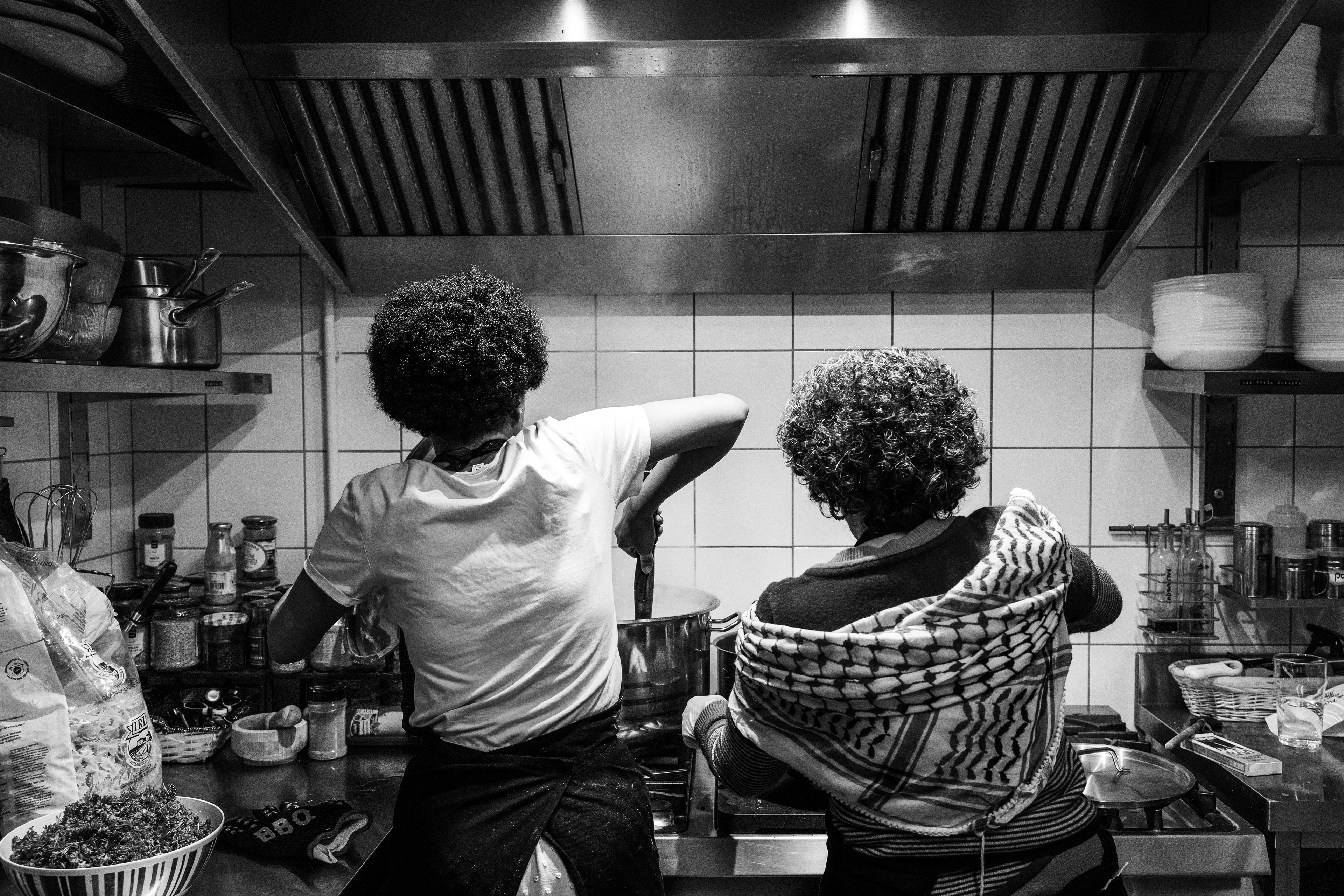 On the left, Maram Hussein and a volunteer are mixing ingredients for the lunch service. The volunteer helps out from time to time to support the team at Darna – formerly a Syrian canteen. 12 December 2025, in Montreuil, France.